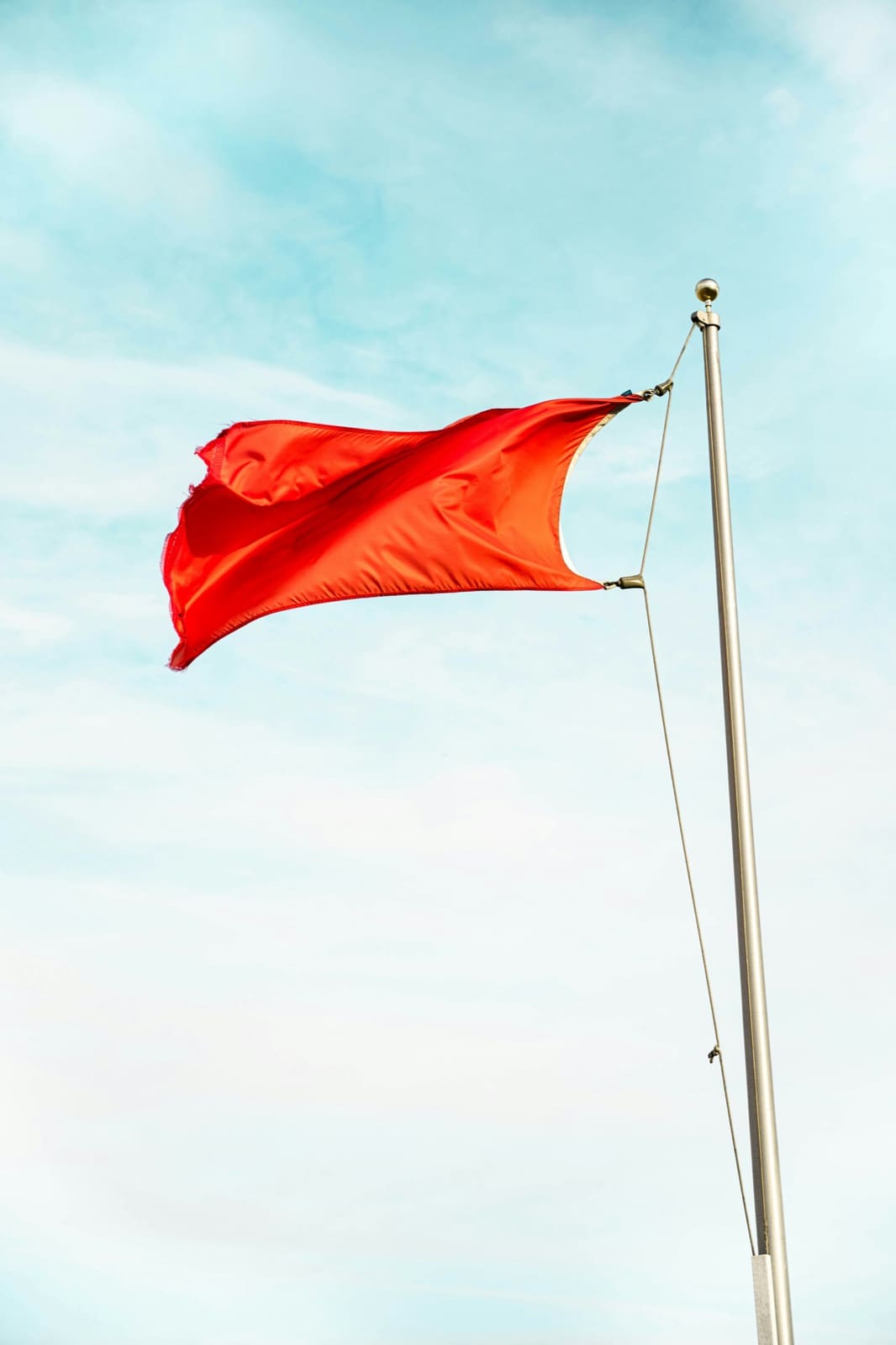 A red flag flying against a blue sky