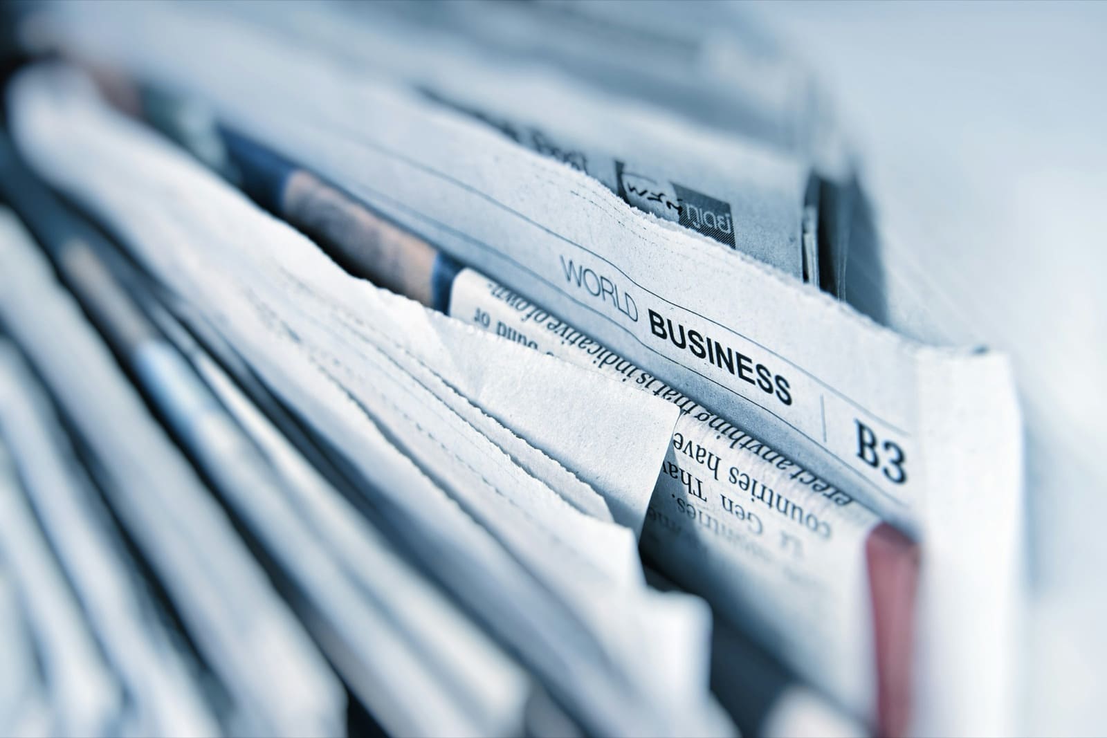 A stack of folded newspapers with a business section visible