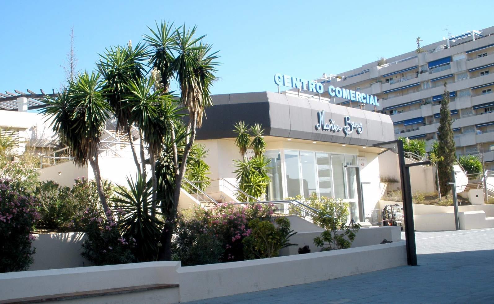 The Centro Comercial building in Nueva Andalucía, Marbella, framed by palms