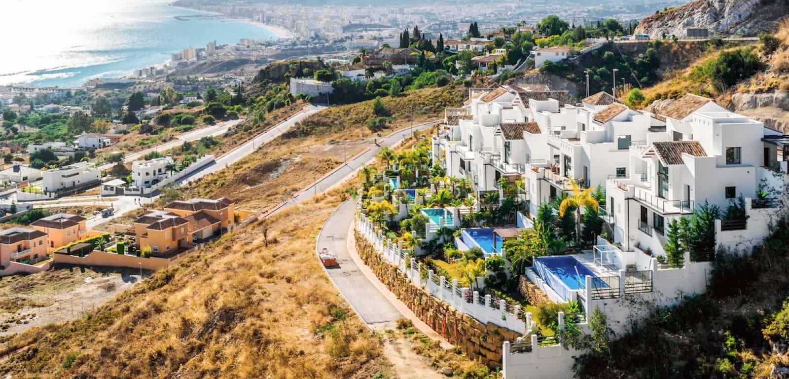 New white townhouses with private pools on a hillside above the Costa del Sol coast