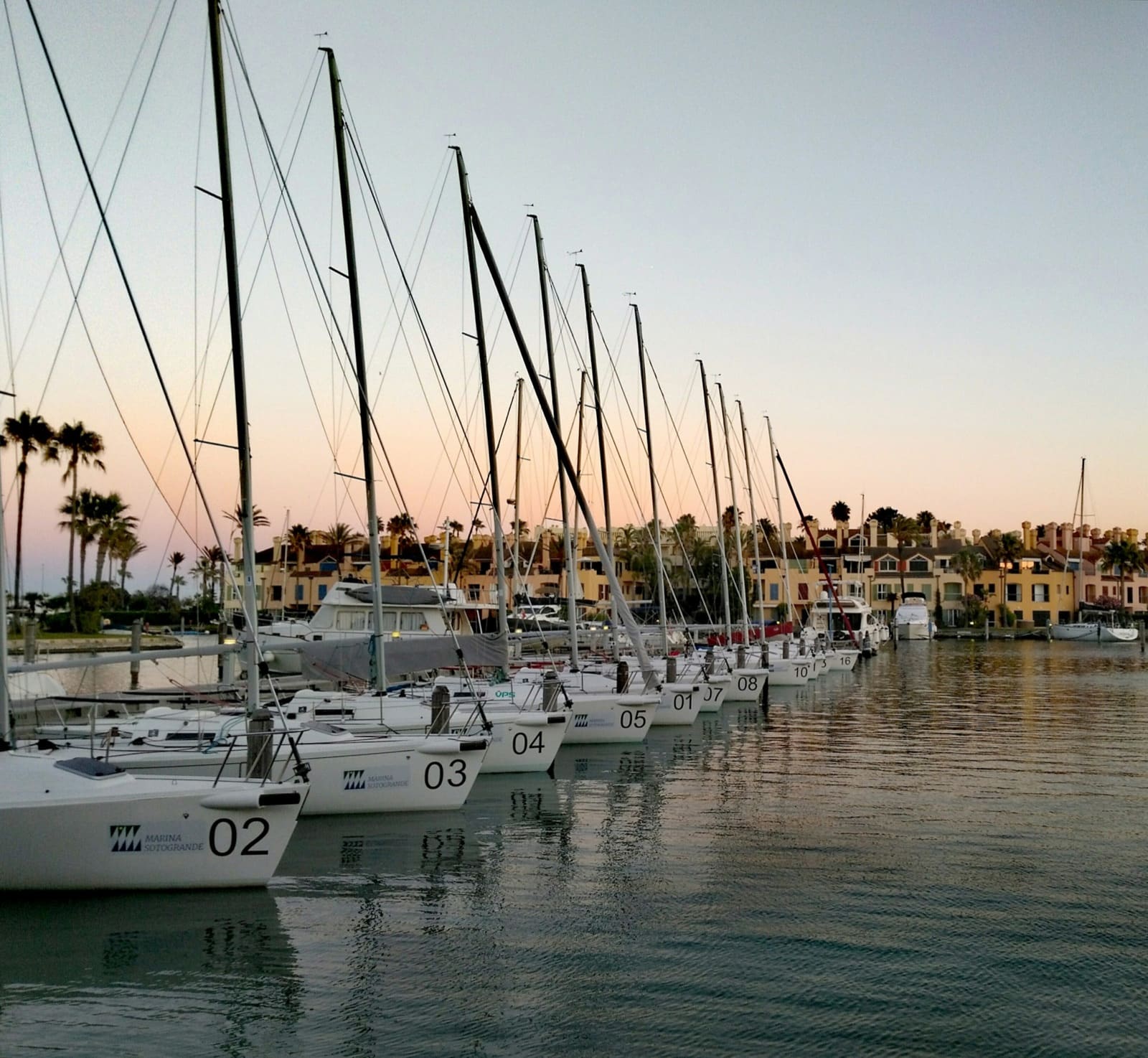Sailing boats moored in Sotogrande marina at dusk, with apartments along the waterfront