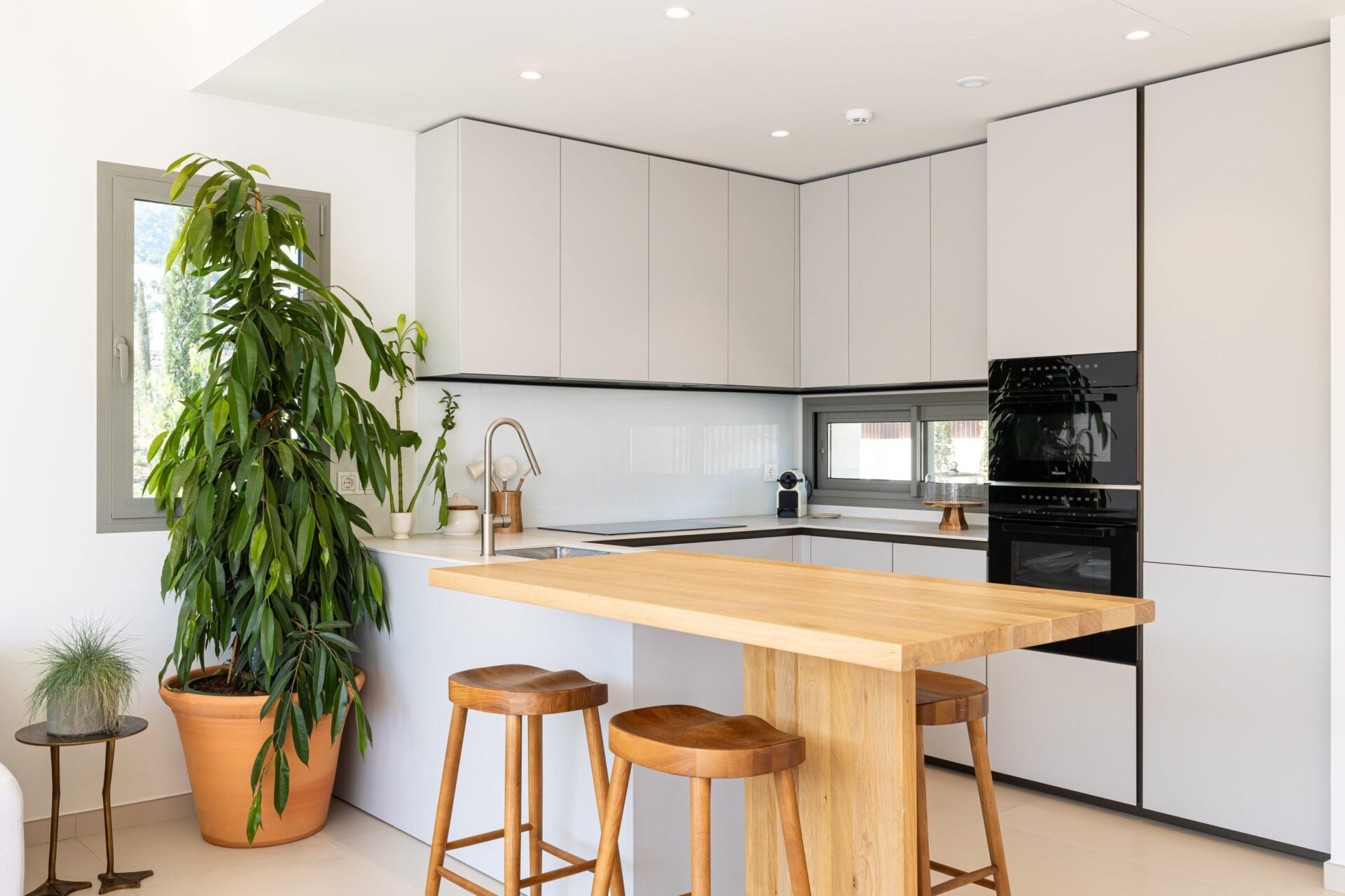 The kitchen, with white cabinets, built-in ovens and a wooden breakfast bar. 16+ Collection, Buenavista, Mijas.
