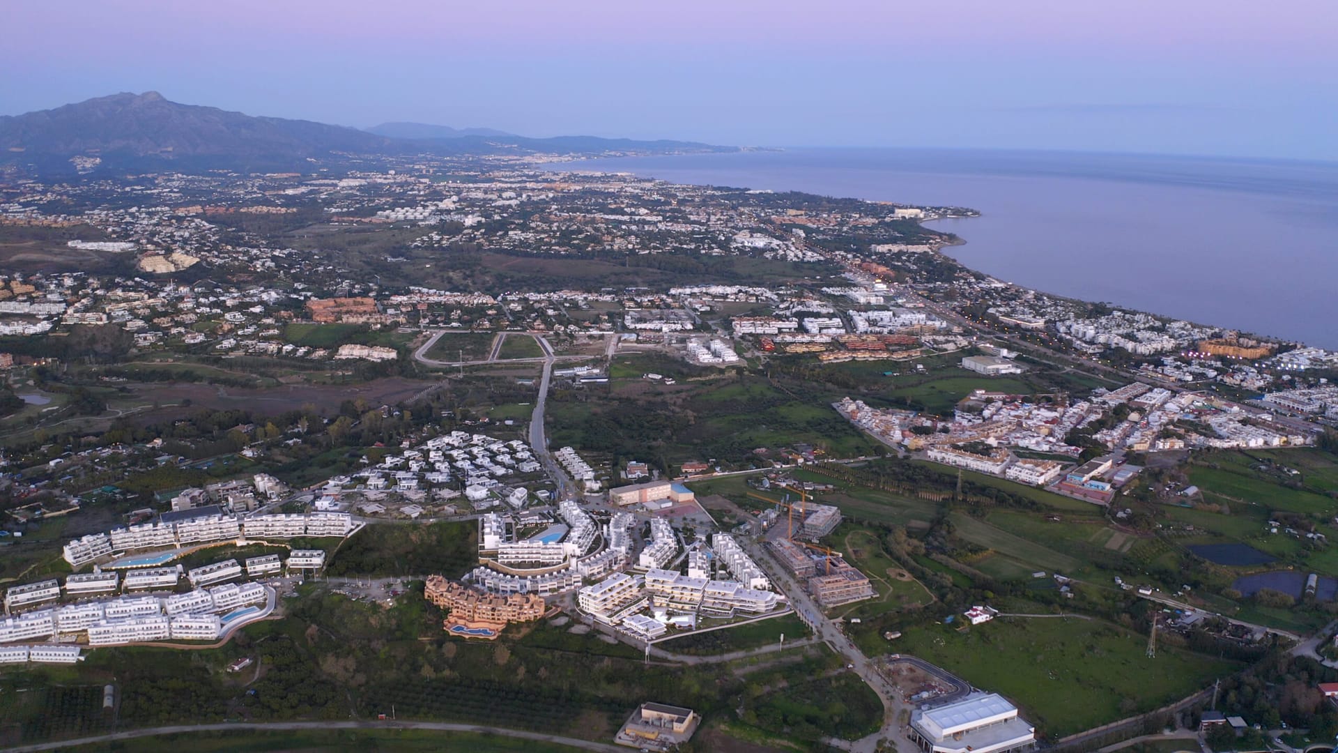 An aerial view of Cancelada at dusk, looking east along the coast towards Marbella and the mountains behind it. Adagio, Cancelada, Estepona.