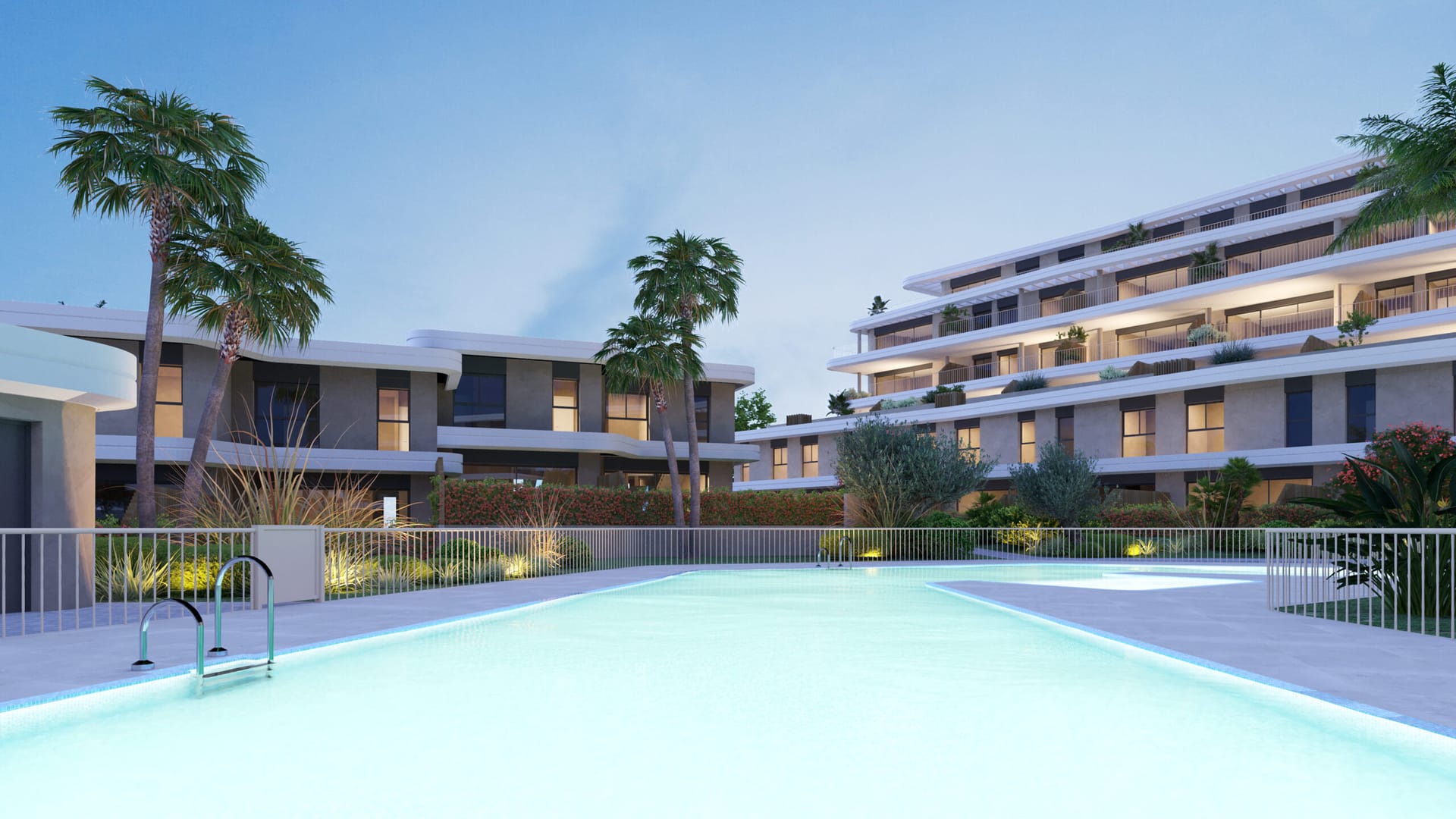 The pool lit up at dusk, with the terraces of the buildings behind. Adagio, Cancelada, Estepona.