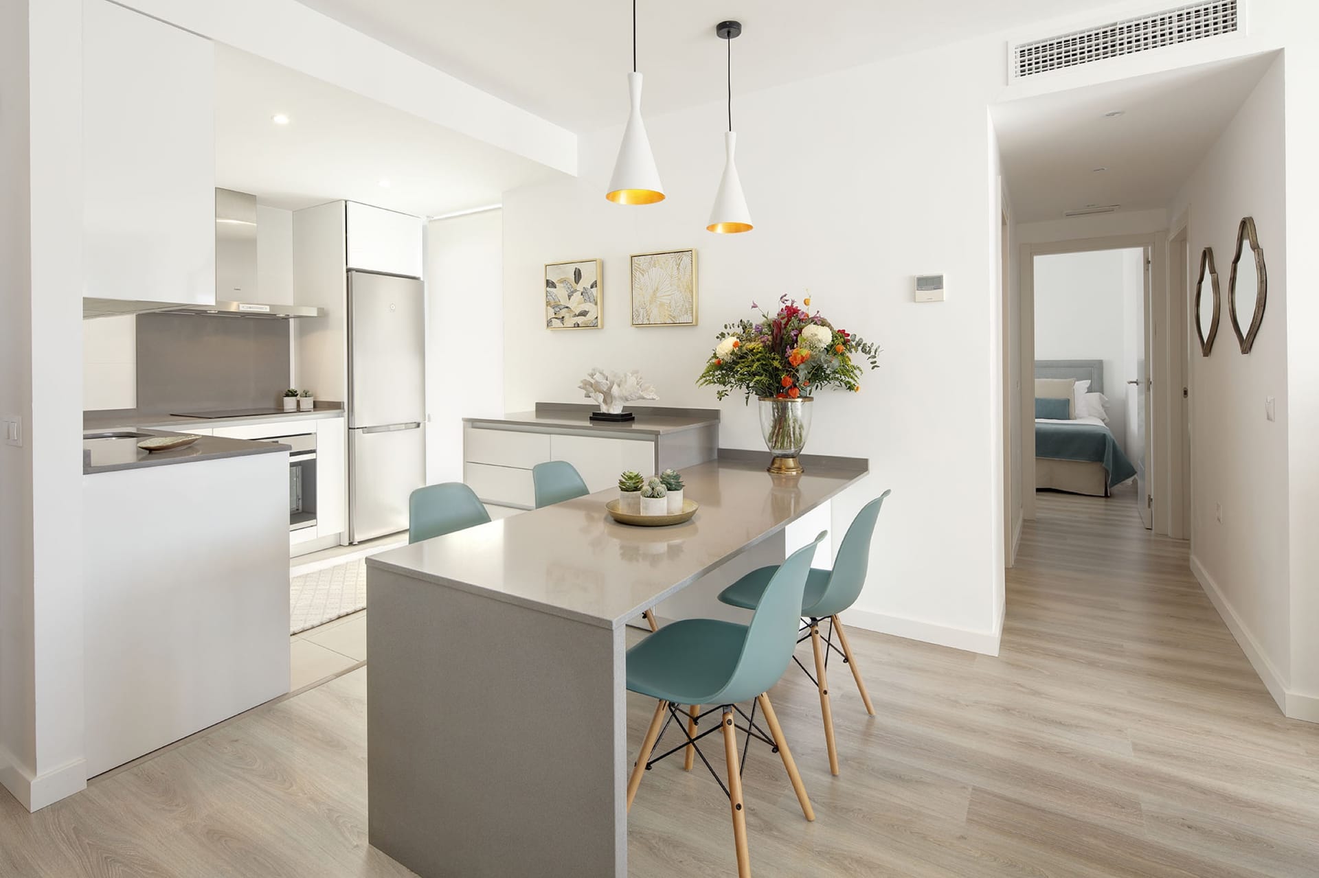 A kitchen in white with a breakfast bar, opening onto the living room. Albatros XV, Nueva Andalucía, Marbella.