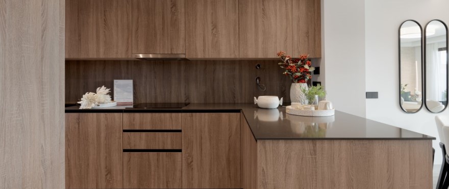 The kitchen, with wood-effect units, a dark grey worktop and a peninsula. Almazara Views, Cerros del Lago, Istán.