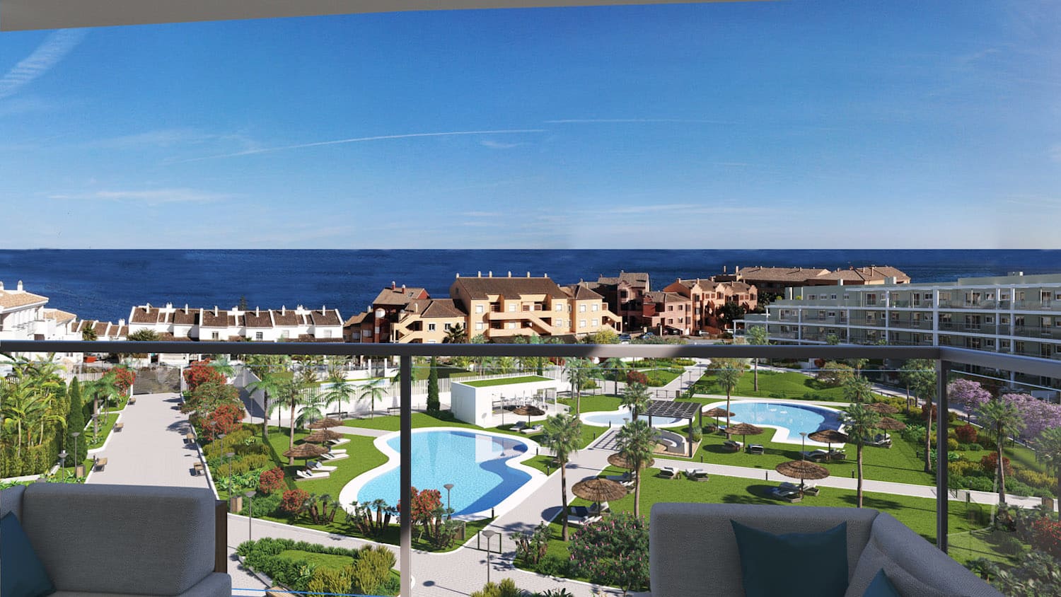 The gardens and two of the pools seen from an upper-floor terrace, with the sea beyond the neighbouring houses. Amphora Beach Residence, La Chullera, Manilva.
