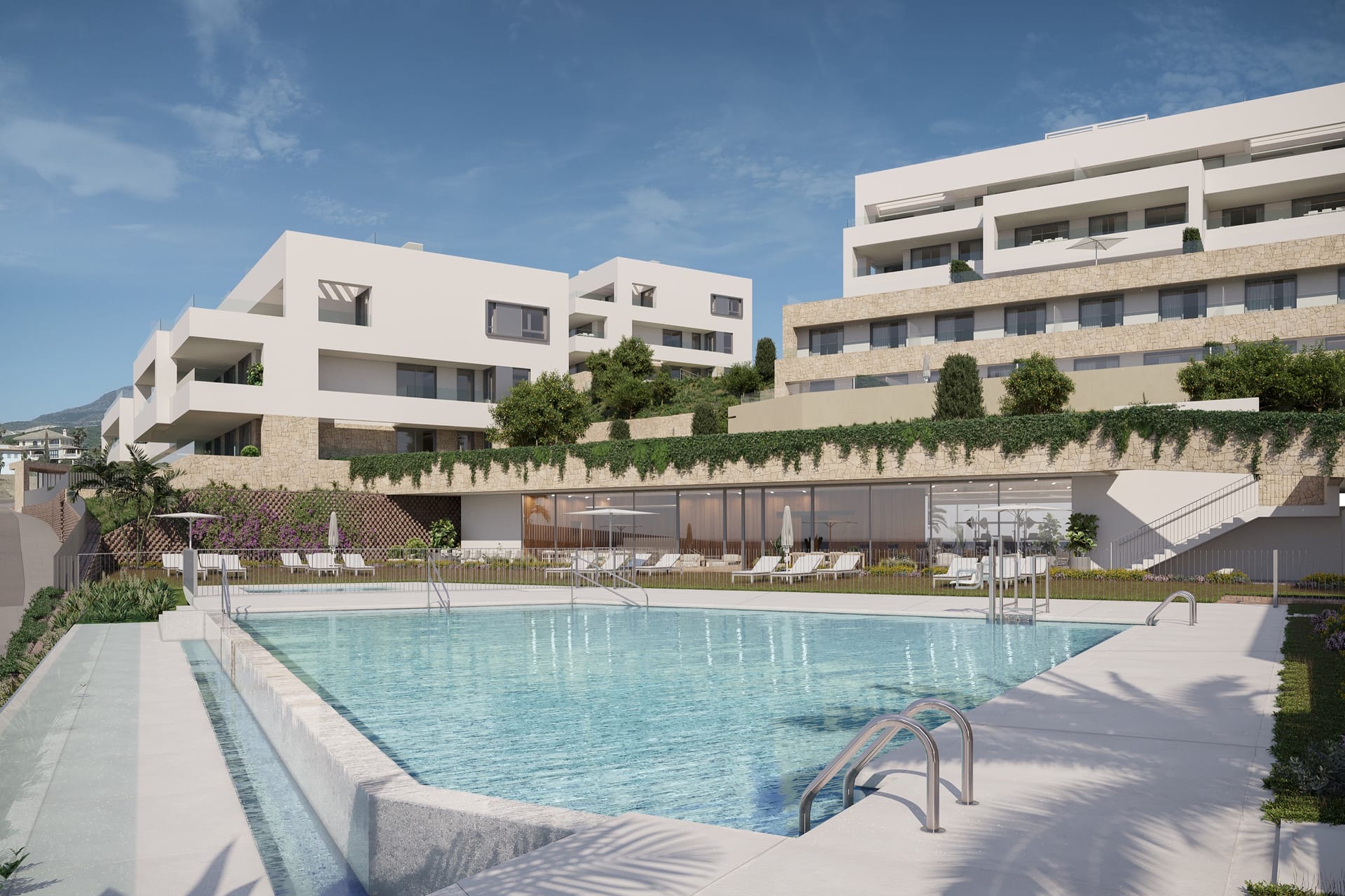 A pool with steps down into it, and the apartment buildings with their planted terraces behind. Azure Estepona, La Gaspara, Estepona.