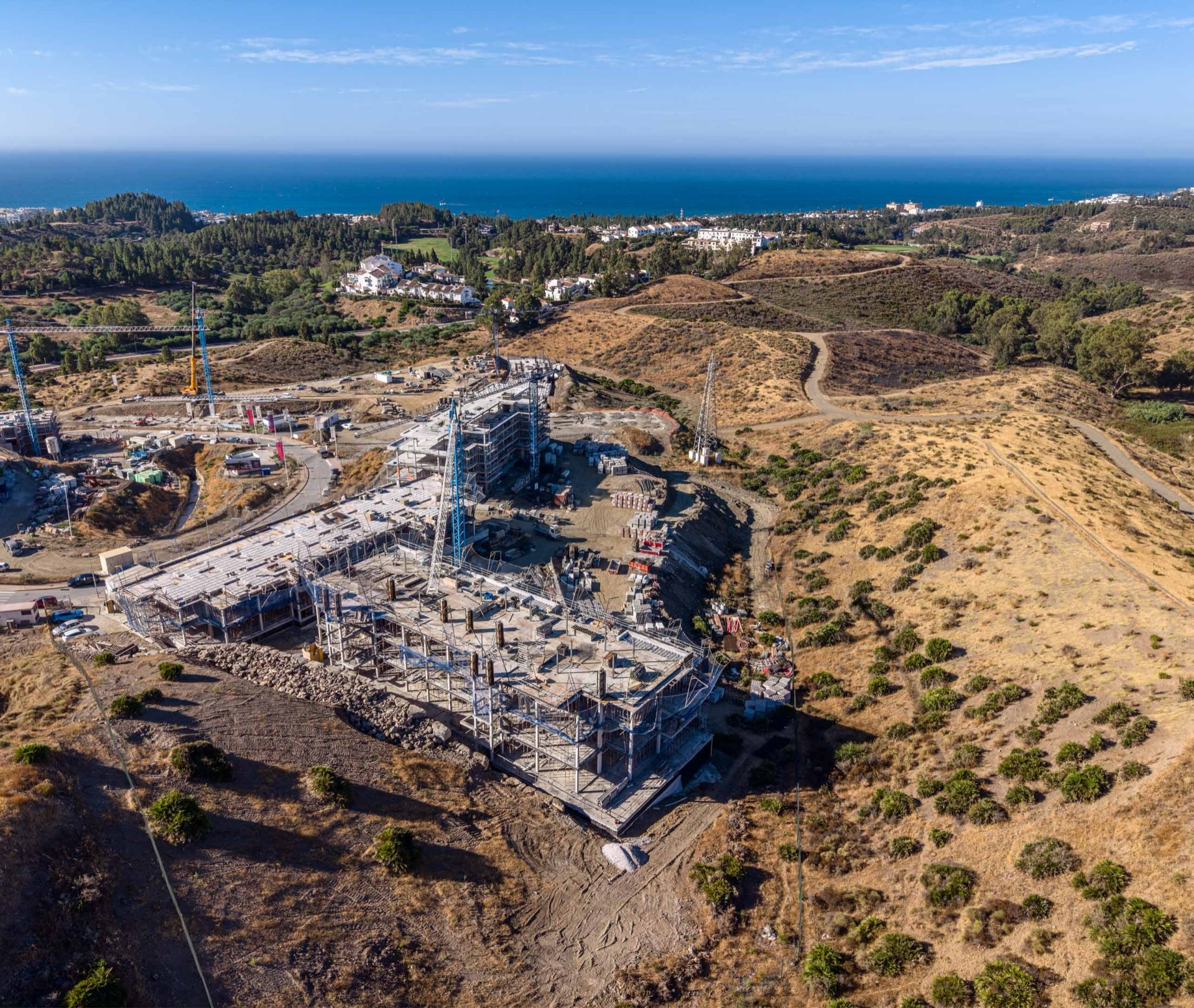 Balance under construction, photographed from the air in August 2026, with the coast beyond. Balance, Hipódromo, Mijas.