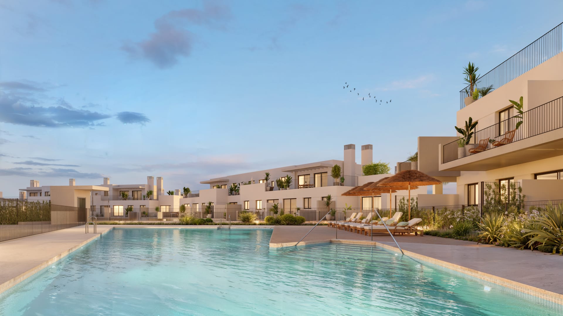 The pool at dusk, with sun loungers under thatched umbrellas and the apartment buildings around it. Baviera Golf, Baviera Golf, Caleta de Vélez.