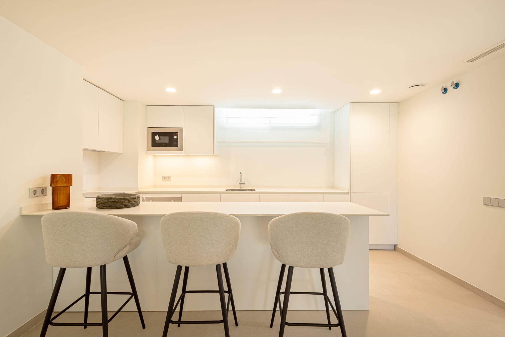 The kitchen in the show apartment, finished in white with a breakfast bar. Breeze, Guadalmina Alta, Marbella.