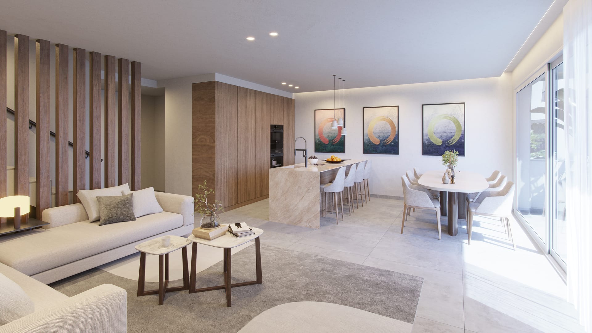 The living room and kitchen as one open space, with walnut units, a peninsula in pale stone-effect porcelain and a round dining table by the window. Buenavista Views, Buenavista, Mijas.