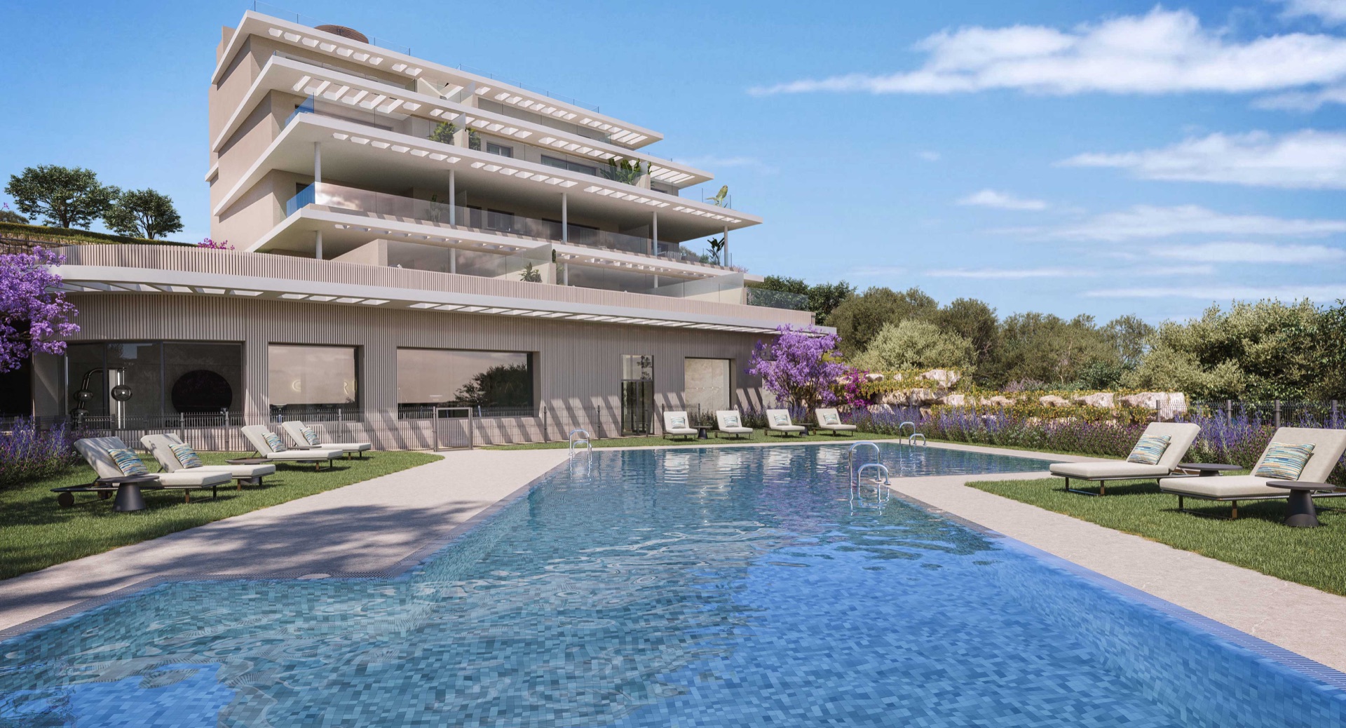 One of the outdoor pools, with sun loungers on the lawn and the buildings behind. Capri, La Resina, Estepona.