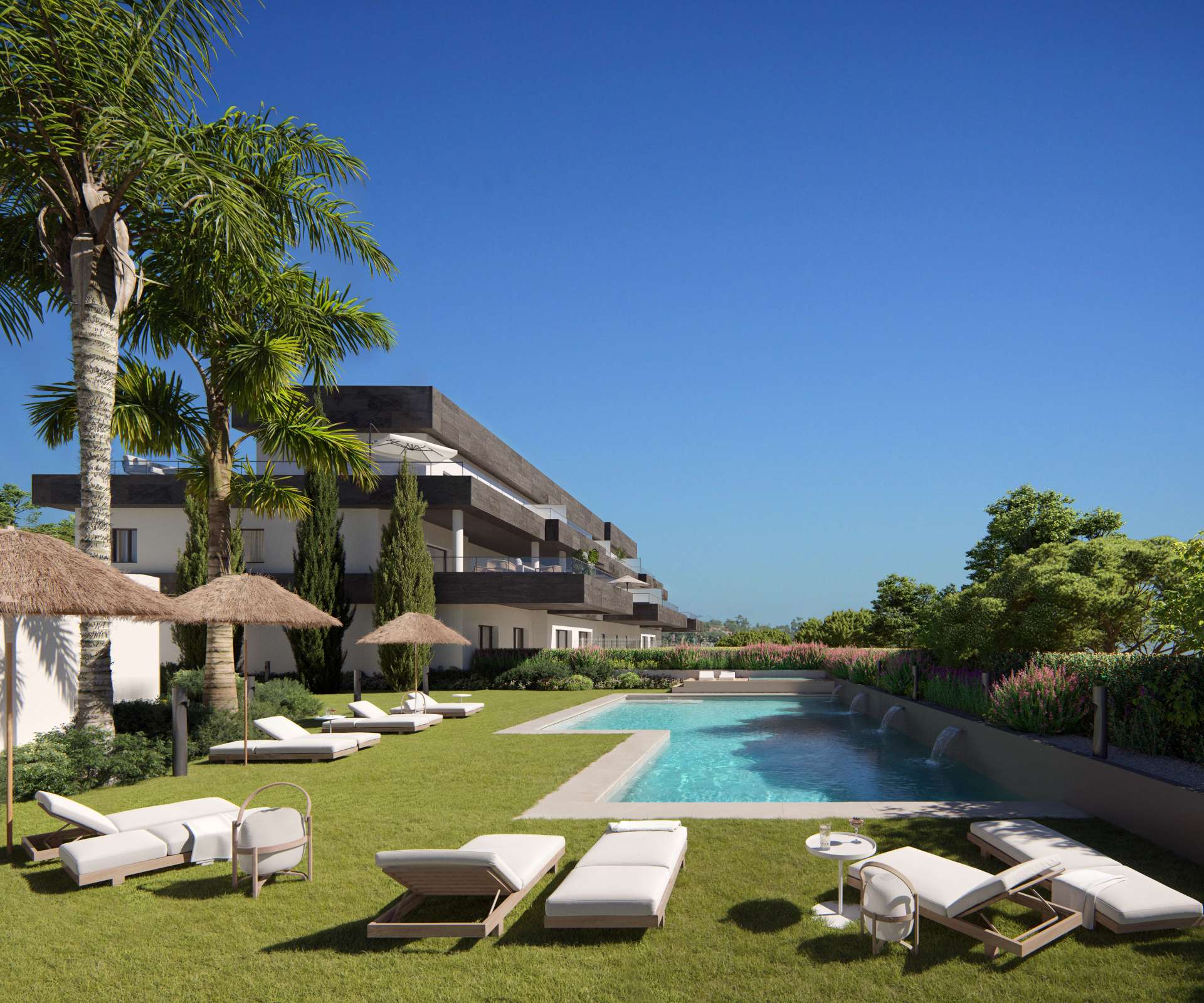The communal pool, with sun loungers on the lawn, straw parasols and palm trees, and one of the buildings behind. Casares Bay, Doña Julia, Casares.