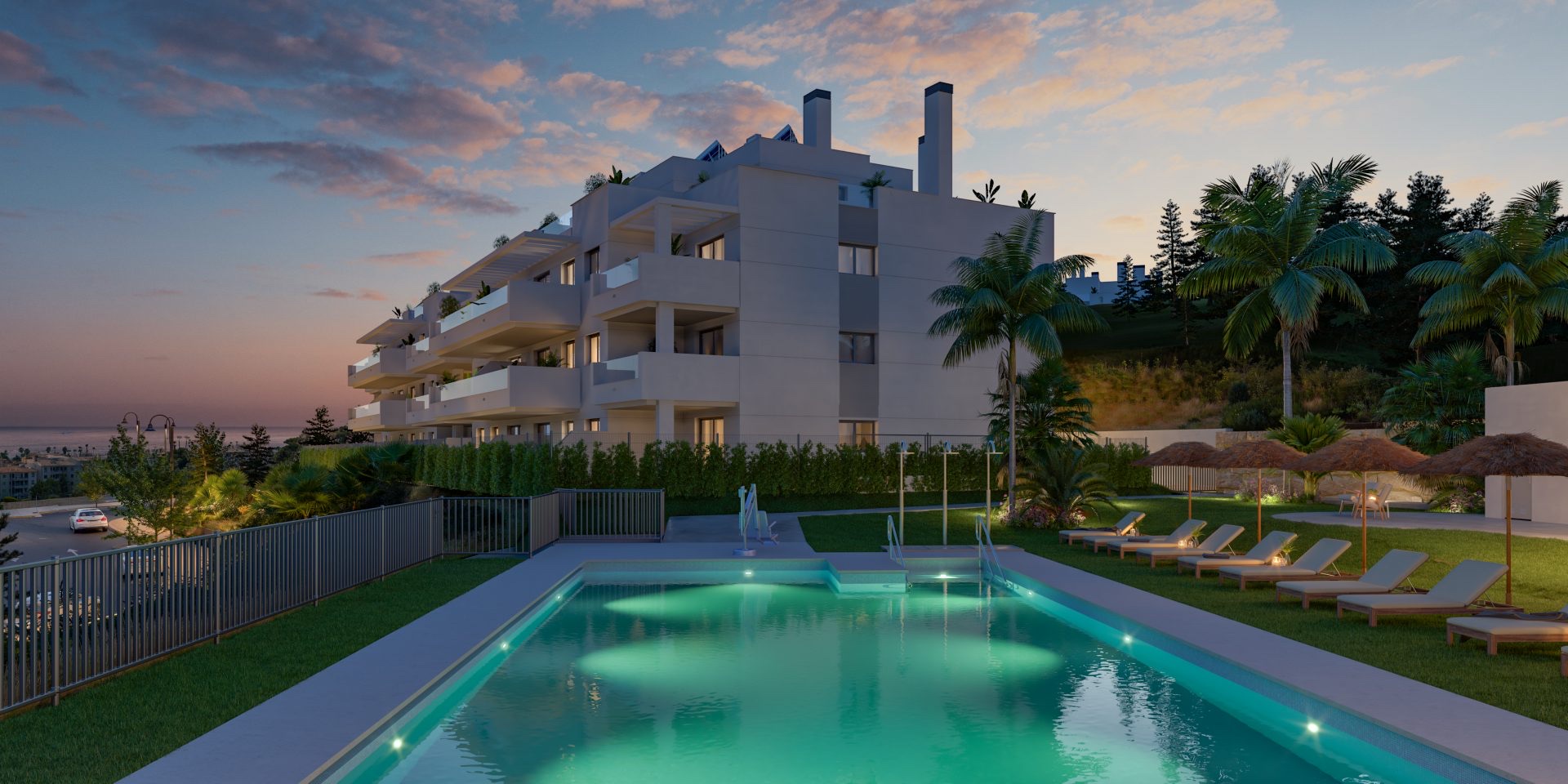 The communal pool at dusk, with sun loungers along one side and the sea beyond. Célere Sunrise, El Chaparral, Mijas.
