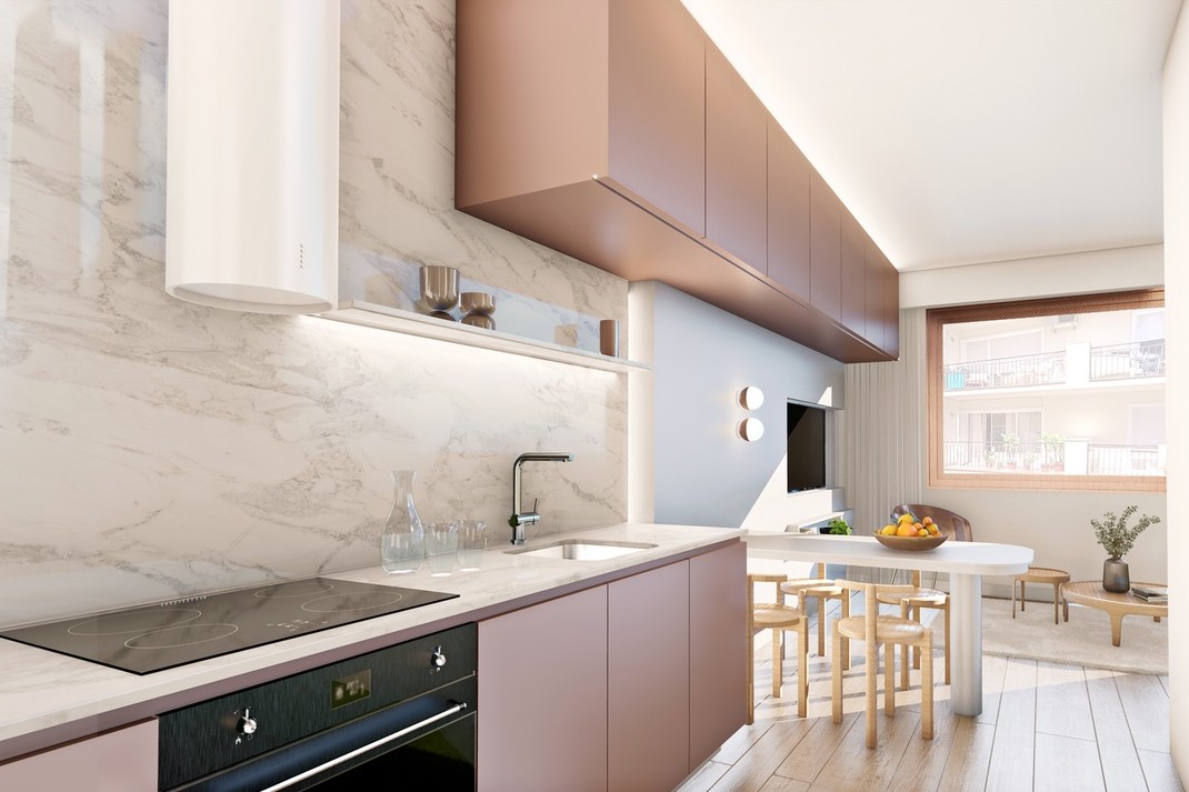 The kitchen along one wall of the living room, with marble-effect tiling behind the worktop, rose-toned cupboards and a small dining table by the window. Edificio Gimena, Town centre, Fuengirola.
