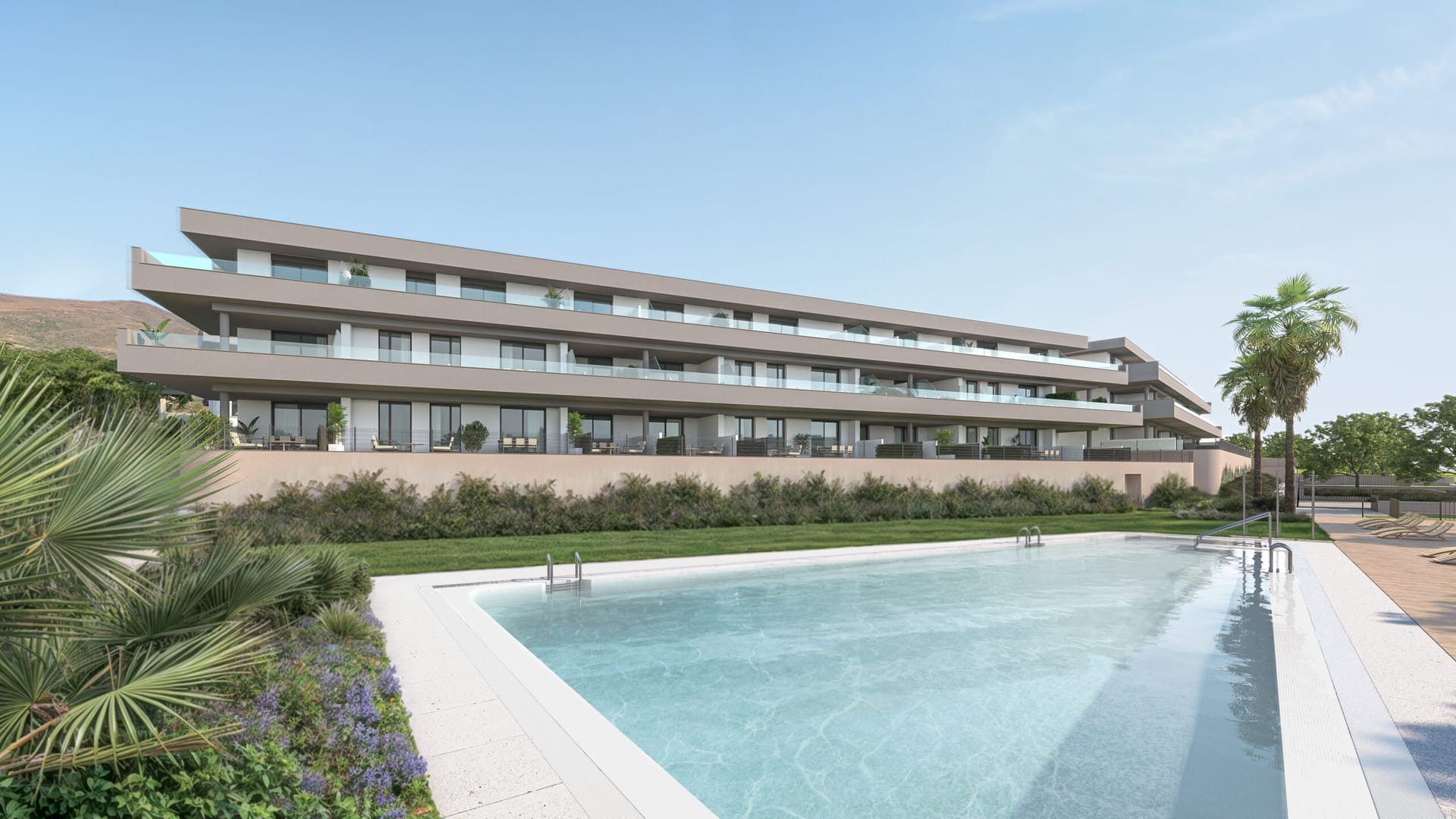 The pool, with a lawn and planted borders in front of the buildings. Etherna Homes, Valle Romano, Estepona.