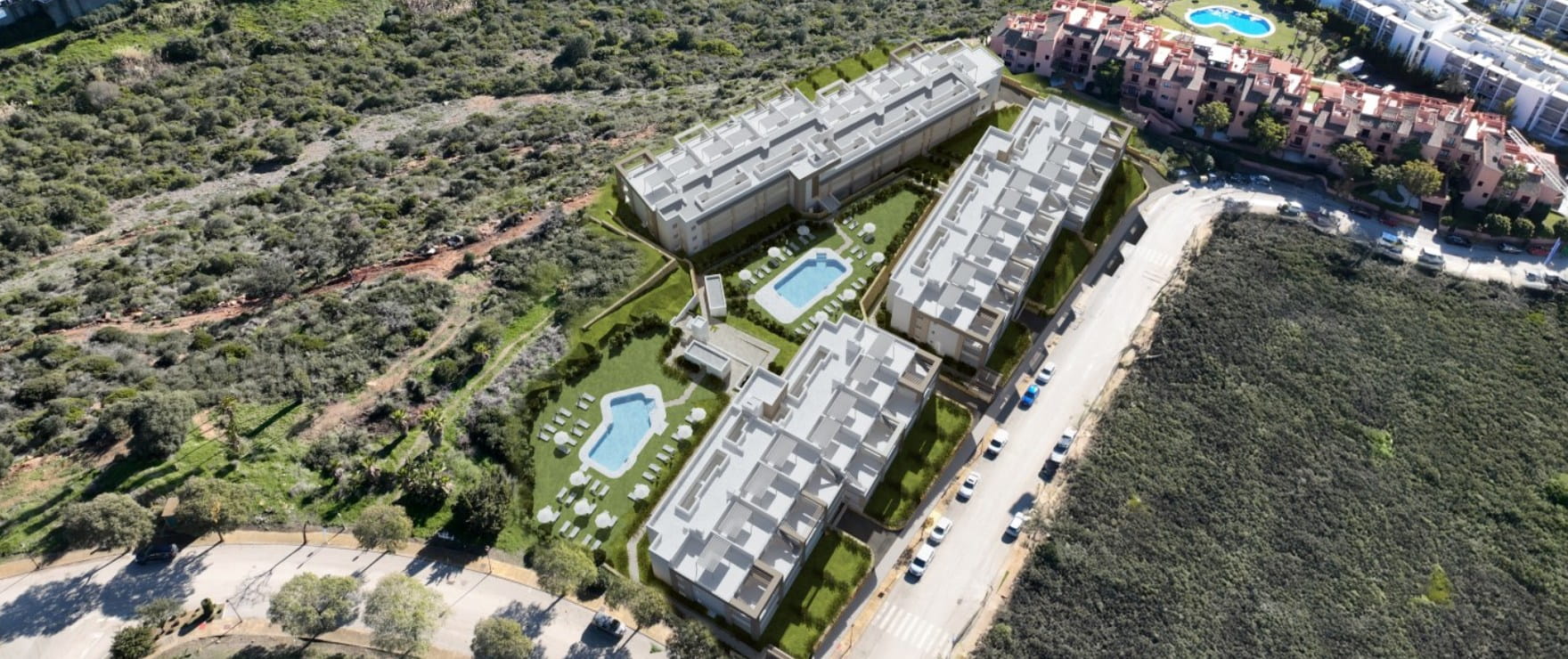 An aerial view of the buildings, with their pools and gardens between them and open hillside around. Grand Bay, Bahía de las Rocas, Manilva.