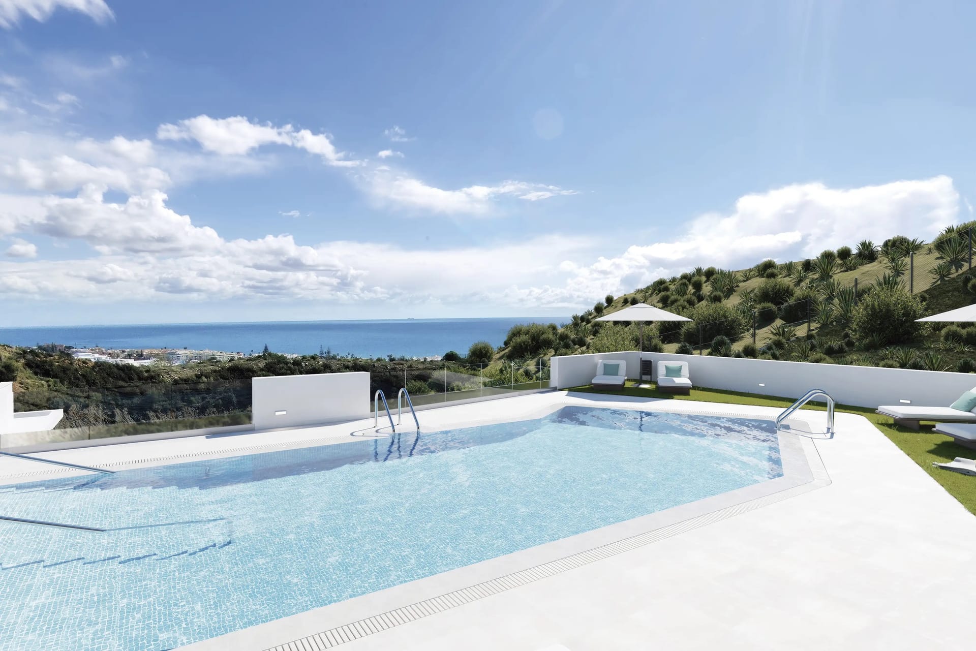 The shared pool at the top of the grounds, with sun loungers on the lawn and the sea beyond. Idilia Terram, Torre de Benagalbón, Rincón de la Victoria.
