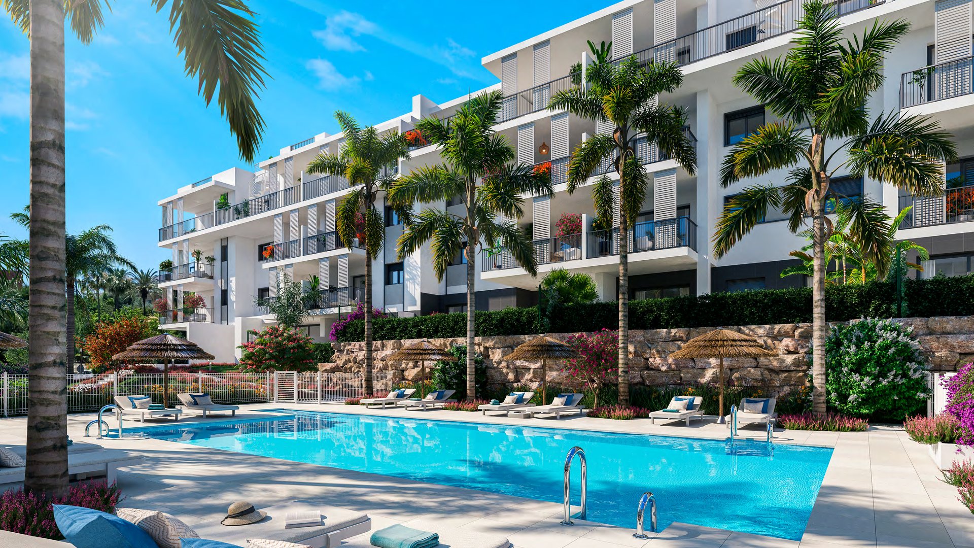 The pool from the garden, loungers along one side and one of the buildings rising behind the planting. Isidora Living, Calle Carlos Cano, Estepona.