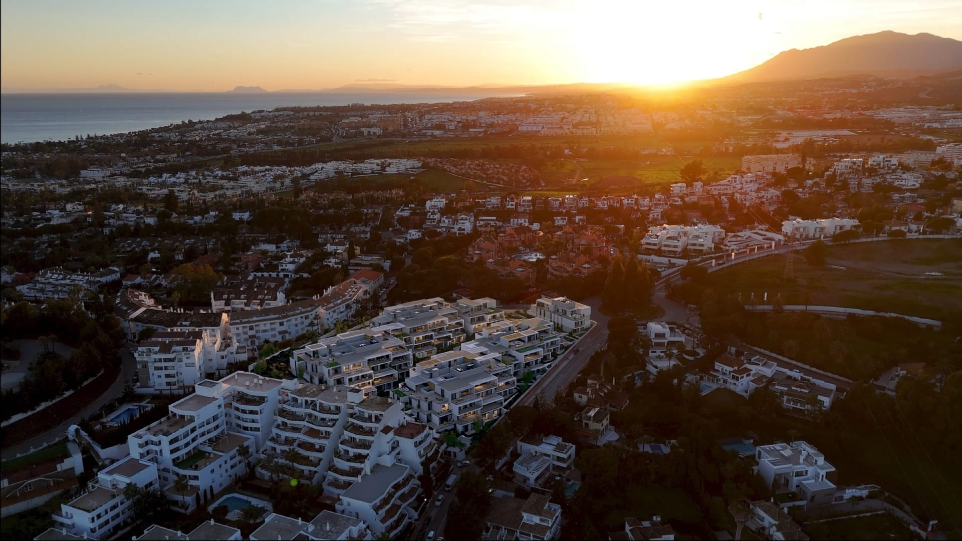 An aerial view of the buildings at sunset, with the coast and the mountains beyond. Isla Bela, Nueva Andalucía, Marbella.