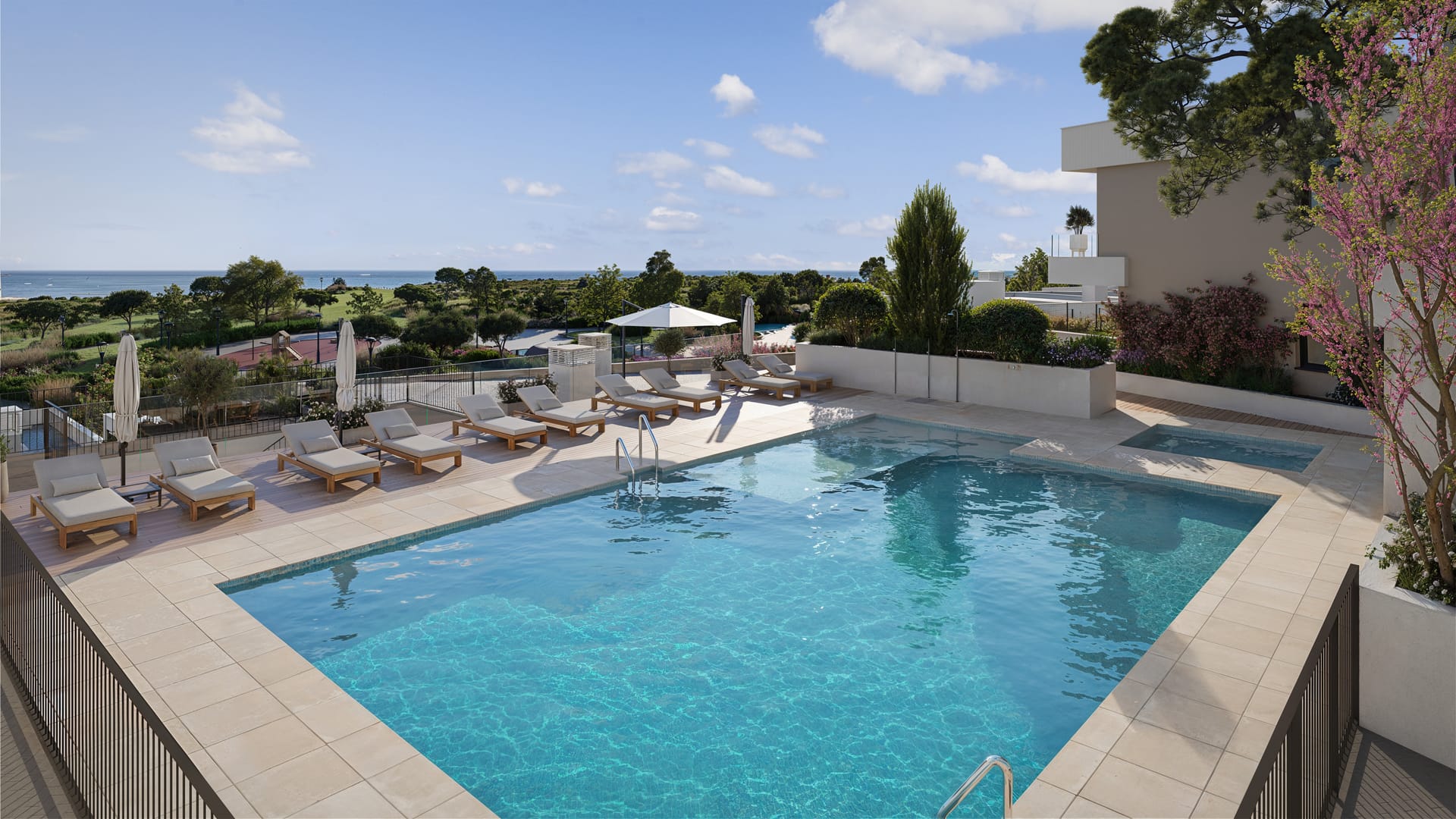 The larger of the two pools, with loungers along its far side and the sea in the distance. Kala Residences, El Higuerón, Fuengirola.