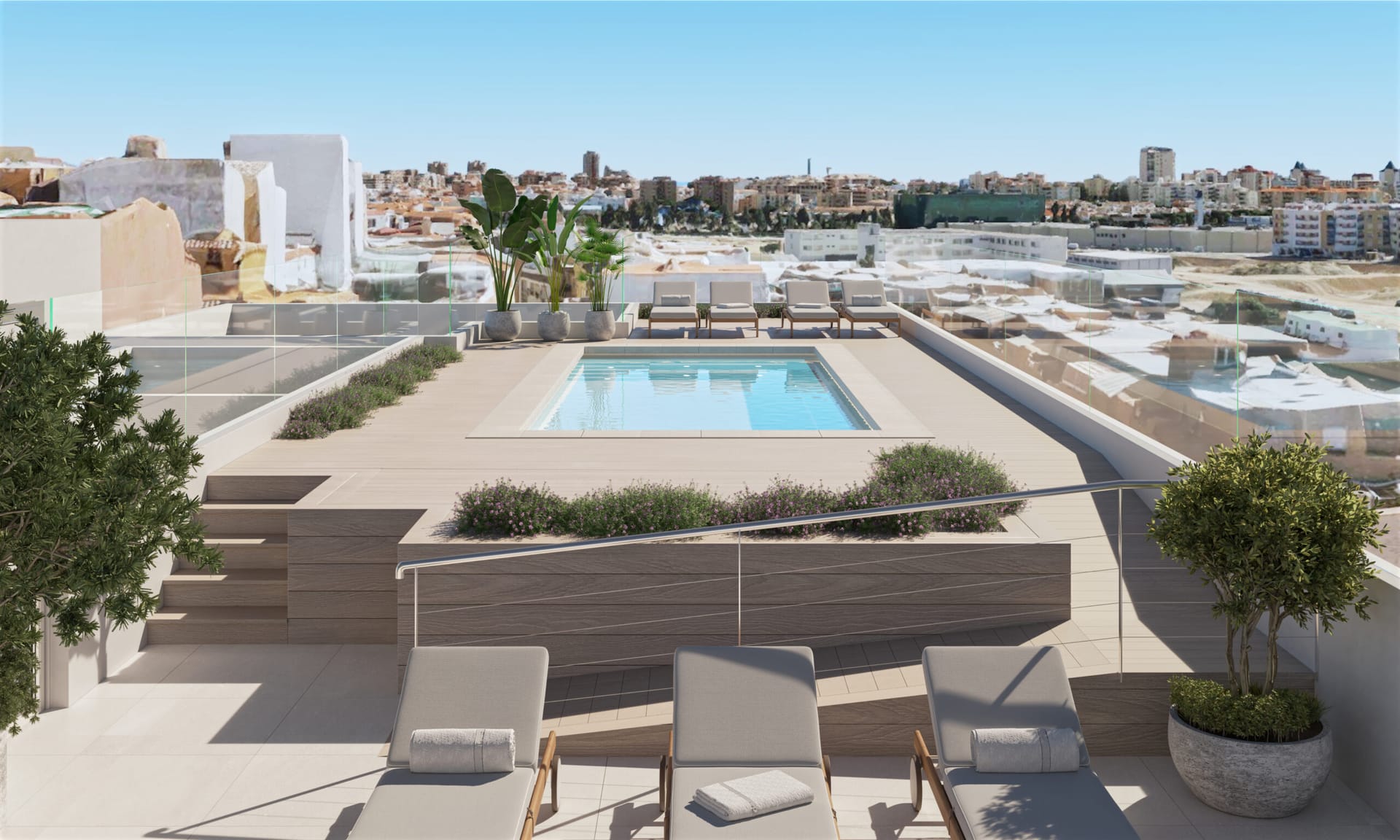 The pool on the roof, with sun loungers along the deck, planters and a glass rail, and the surrounding rooftops beyond. Laguna Nova, Las Lagunas, Mijas.