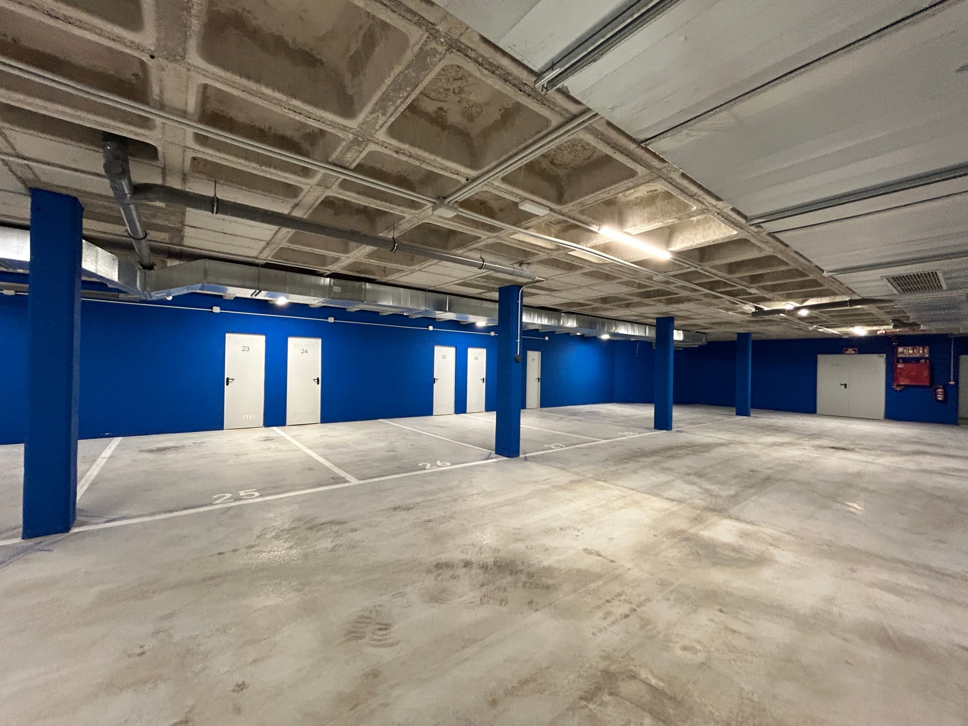 The shared garage, with numbered parking spaces and a row of storeroom doors along the blue wall. Lomas del Higuerón 2, El Higuerón, Fuengirola.