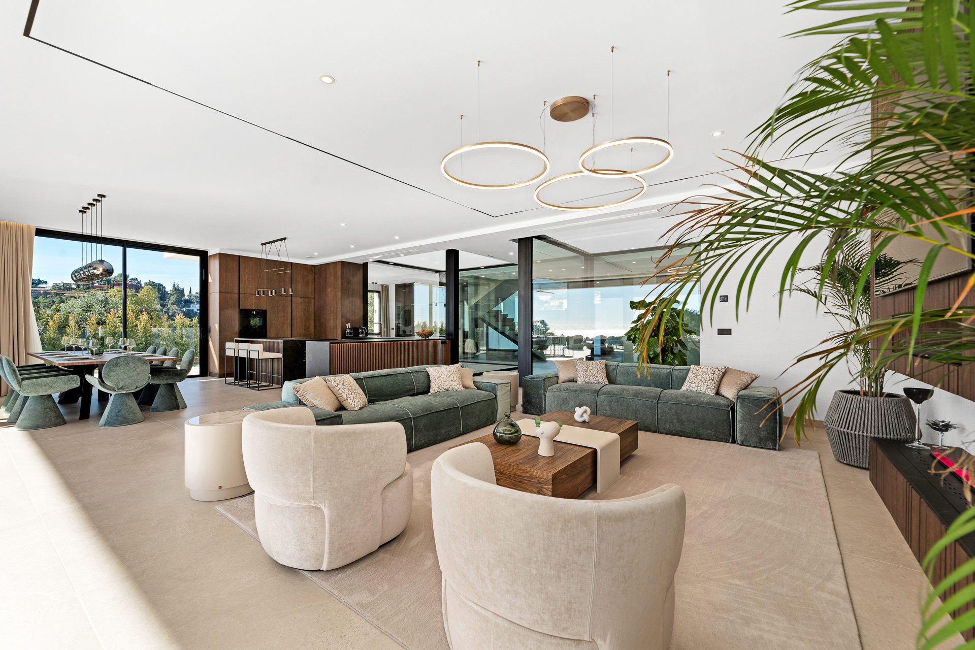 The living room of one of the villas, furnished, with the dining area and glass doors to the terrace behind. Madroñal Gold, El Madroñal, Benahavís.