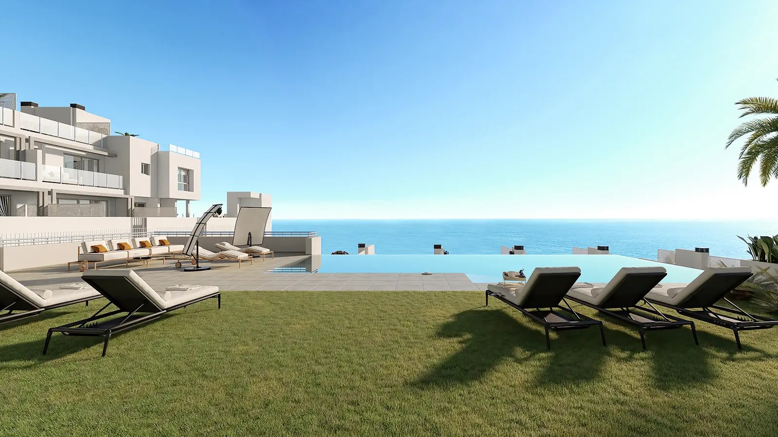 The infinity pool and a lawn with sun loungers, with the sea beyond the edge of the pool. Mary’s Hill, El Peñoncillo, Torrox.