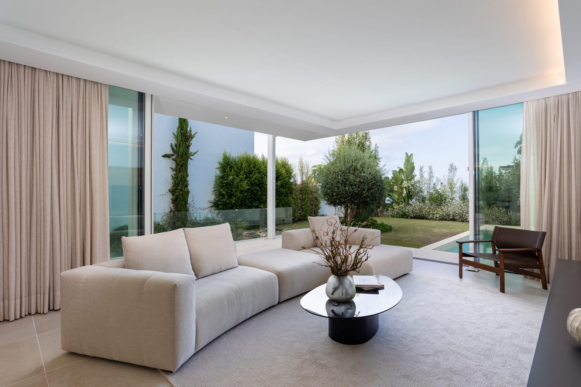The living room of the finished villa, with glass doors open to the garden. Nara Marbella, Valdeolletas, Marbella.