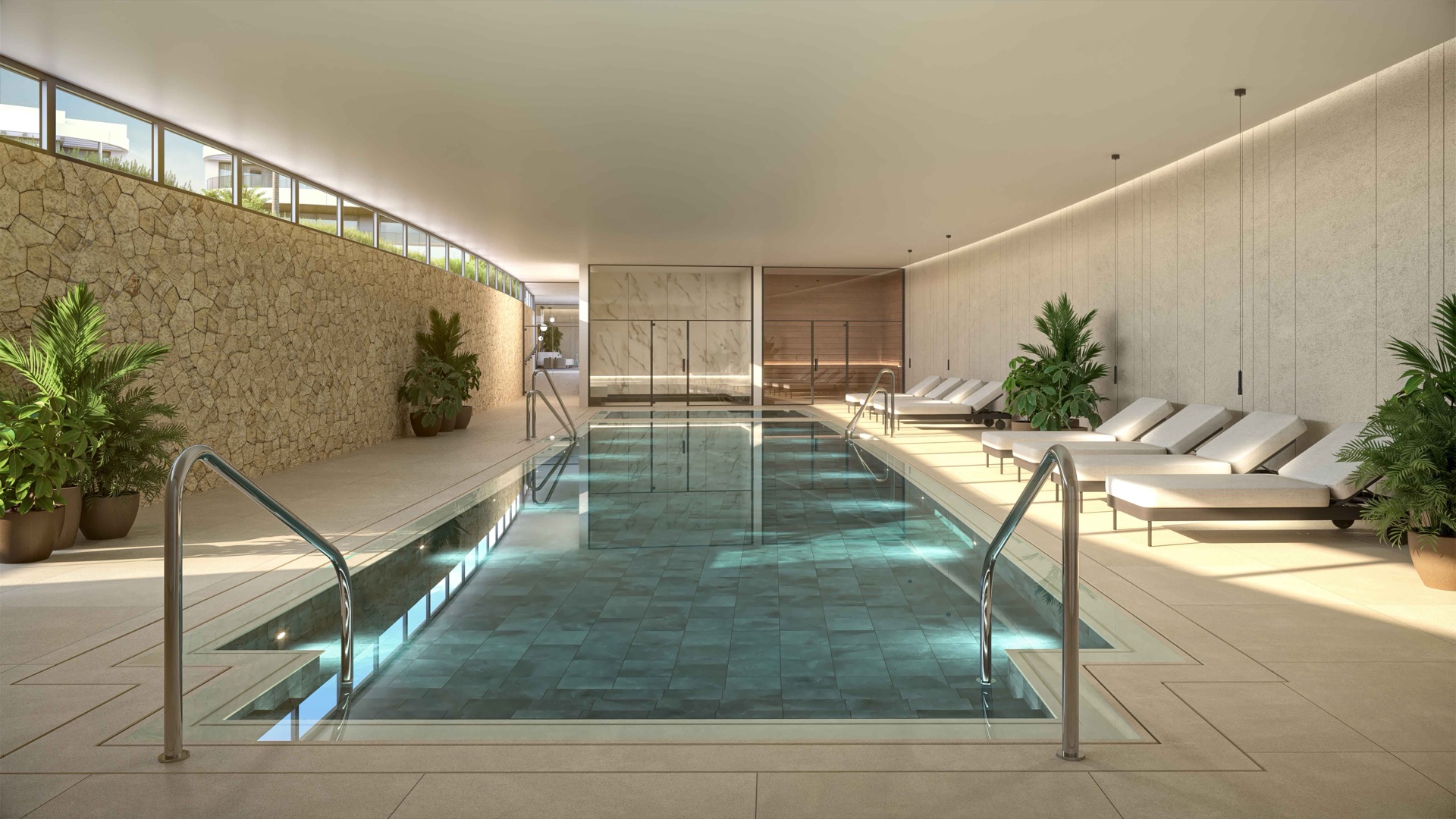 The heated indoor pool, with loungers along a stone wall under a long rooflight. Naya Residences, Atalaya, Estepona.