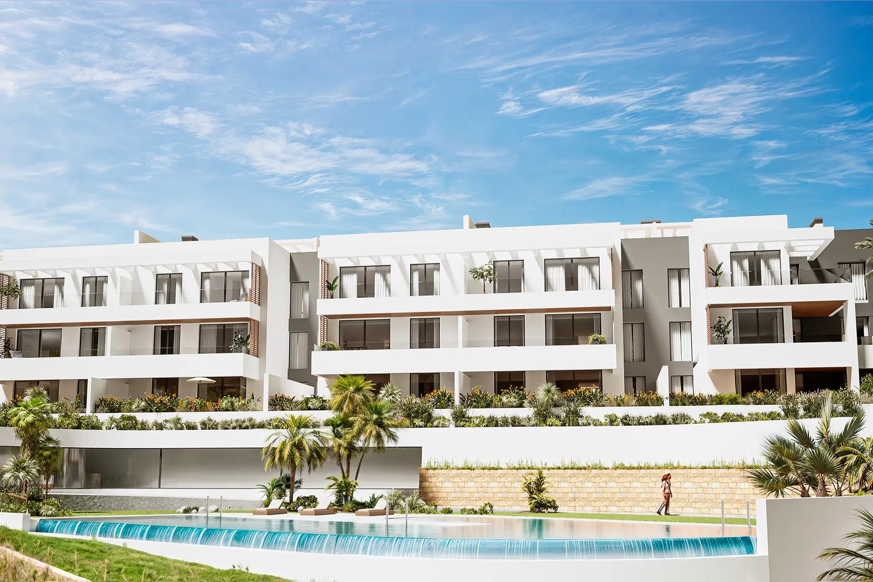 The long white face of one of the buildings, seen across the water of the pool. Nylva Homes, La Paloma, Manilva.