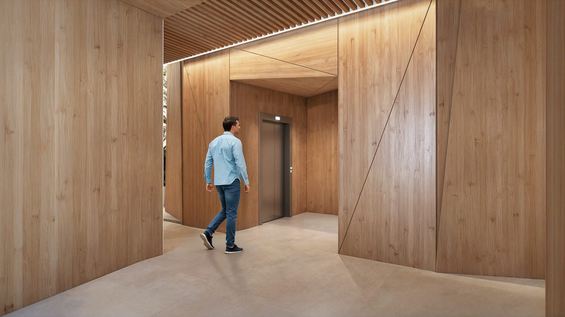 The entrance lobby, lined in pale timber panels, with a slatted timber ceiling and the lift at the far end. Octavia, Carretera de Cádiz, Málaga.