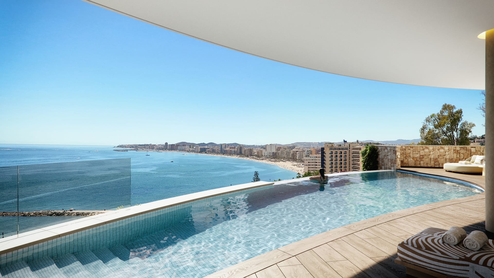 The infinity pool and its timber deck, with the beach and the buildings of Fuengirola along the bay beyond. Óleo, Carvajal, Fuengirola.