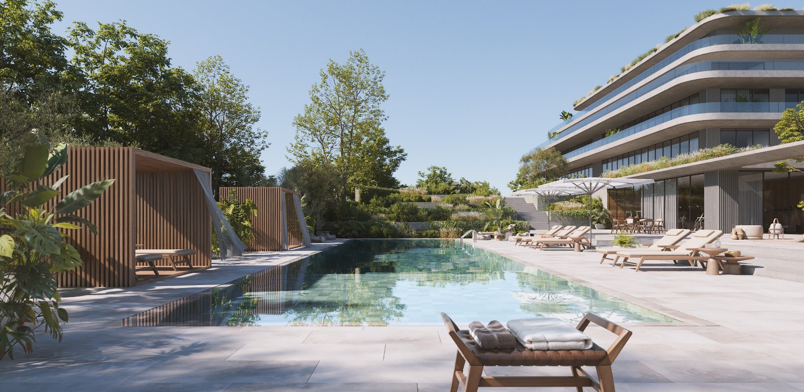 The pool, with timber cabanas along one side, loungers along the other and one of the buildings behind. One Estepona, La Gaspara, Estepona.