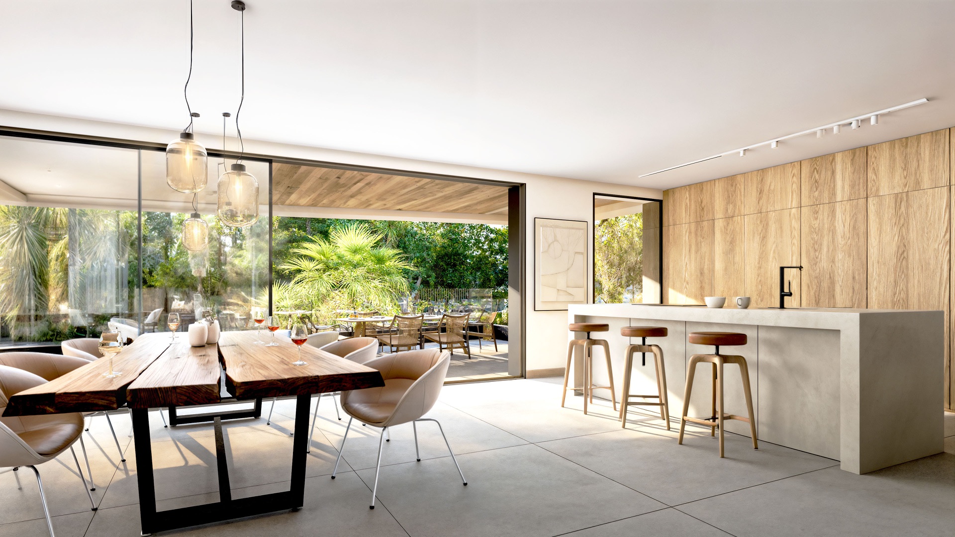 The dining table and kitchen island of a home, with glass doors open to the terrace. Palm Residences, La Resina, Estepona.