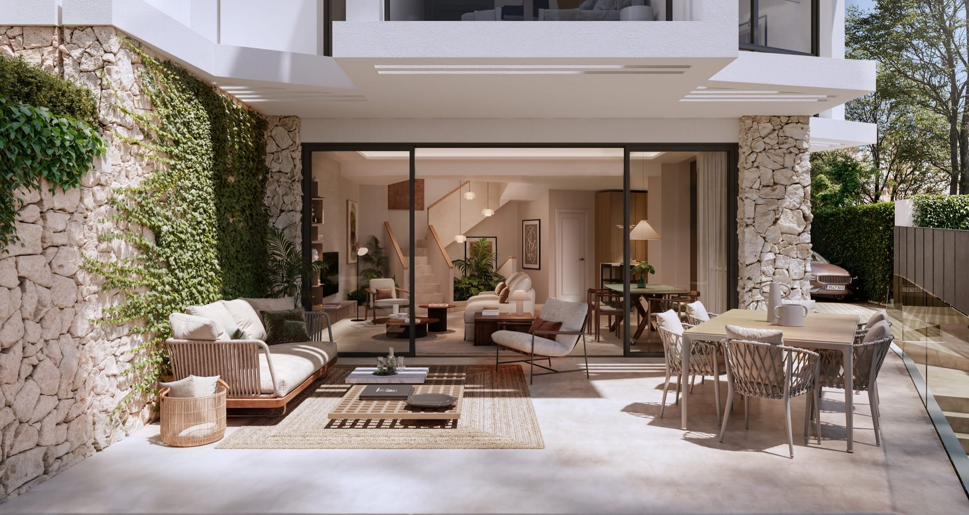 A covered terrace with outdoor sofas and a dining table, open through a glass wall to the living room. Portugal 2, Pedregalejo, Málaga.