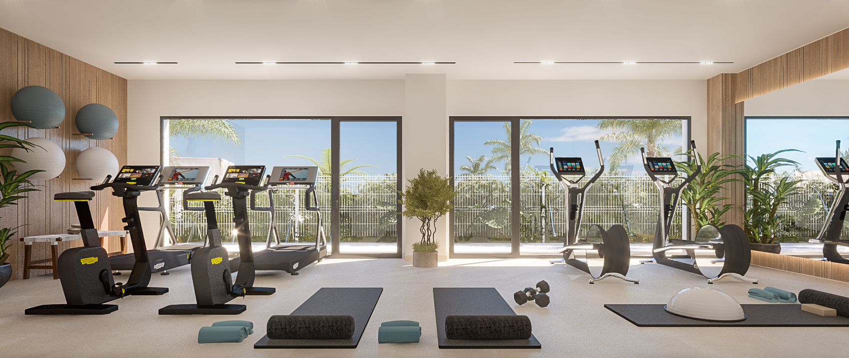 The shared gym, with treadmills and exercise bikes facing a wall of windows. Pure Sun 2, Sabinillas, Manilva.