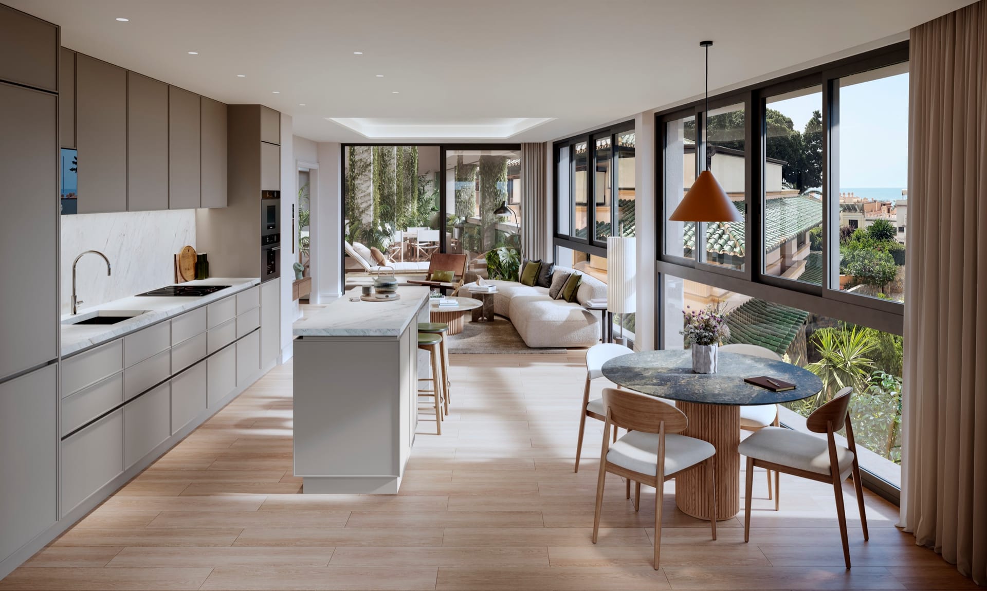 An open kitchen with an island, a round dining table and a lounge along a wall of tall windows. Ramal de Monte Sancha, Monte Sancha, Málaga.