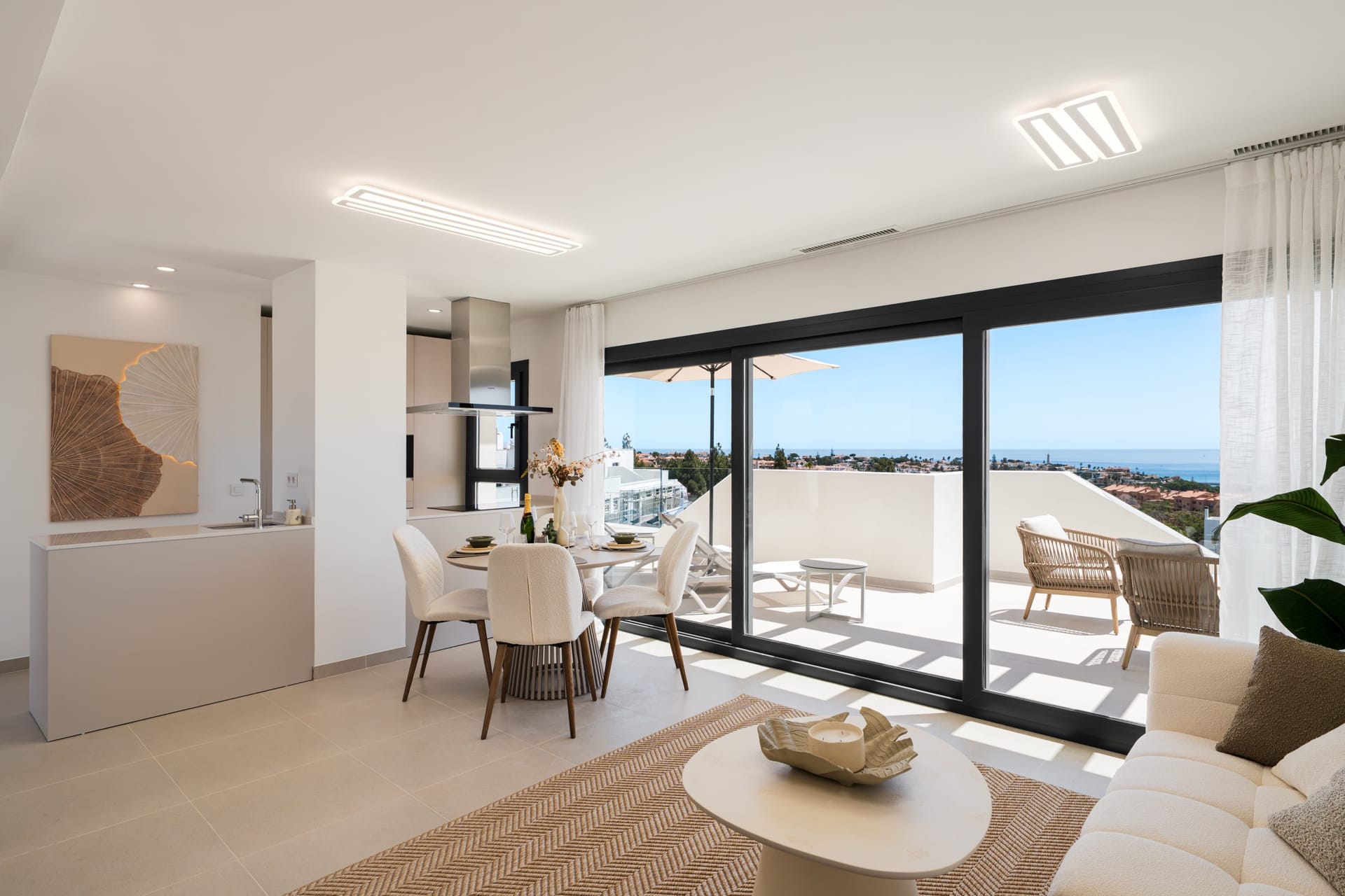 The living and dining room of the show apartment, with sliding glass doors onto the terrace and the sea beyond. Rayos del Sol, El Chaparral, Mijas.