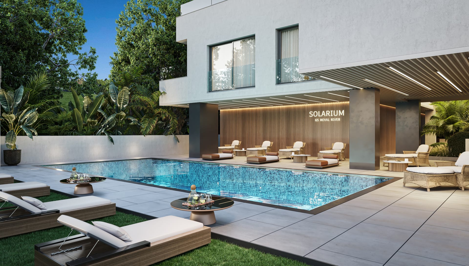 The outdoor pool and its solarium, with loungers under a covered terrace at the foot of the building. Royal River, Río Real, Marbella.
