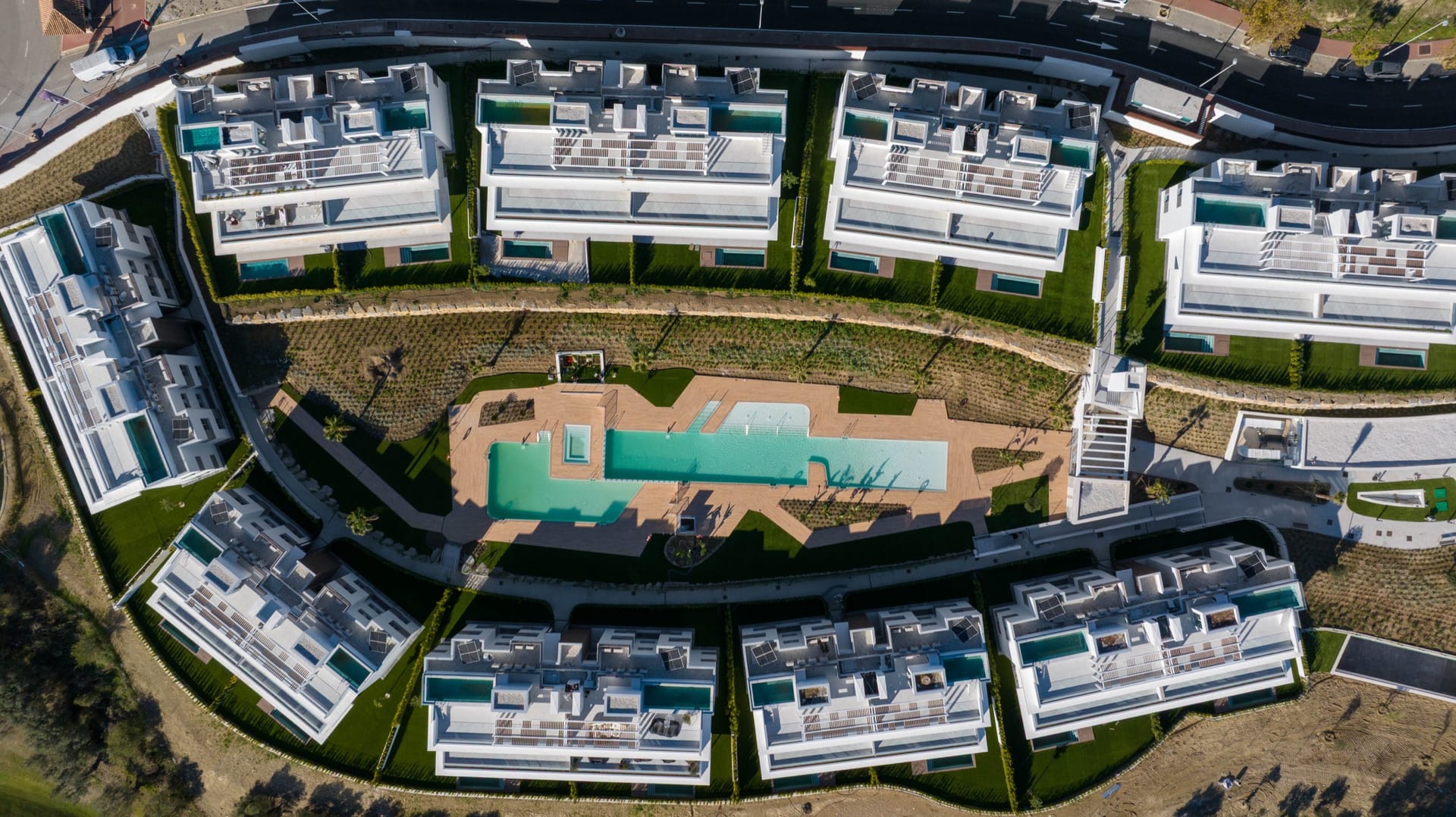 An aerial view of the buildings around their pool, with the golf course beside them. Santa Clara Homes, Los Monteros, Marbella.