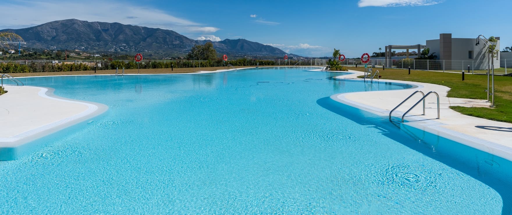 The pool, shaped like a lagoon with a gently sloping edge, and the mountains beyond. Solana Village, La Cala Golf, Mijas.