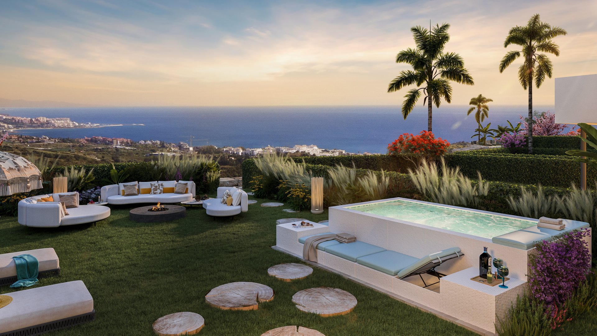 A garden terrace at dusk, seating and a fire table on the lawn, palms behind them and the coast below. Las Terrazas de Cortesín Bon Air, Finca Cortesín, Casares.
