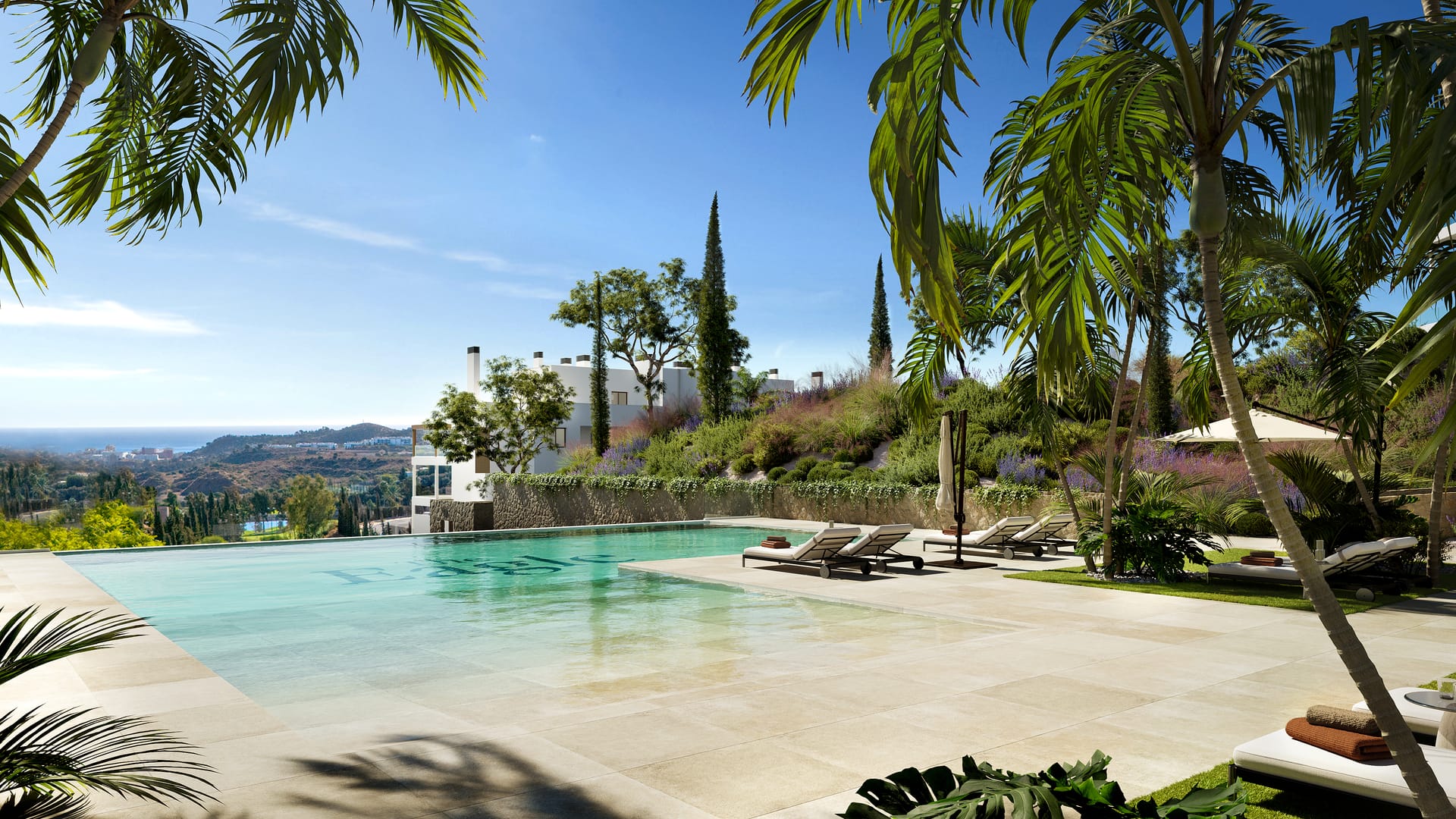 The infinity pool and its stone deck, framed by palm trees, with the hills running down to the sea beyond the far edge. The Eagle Residences, Hipódromo, Mijas.