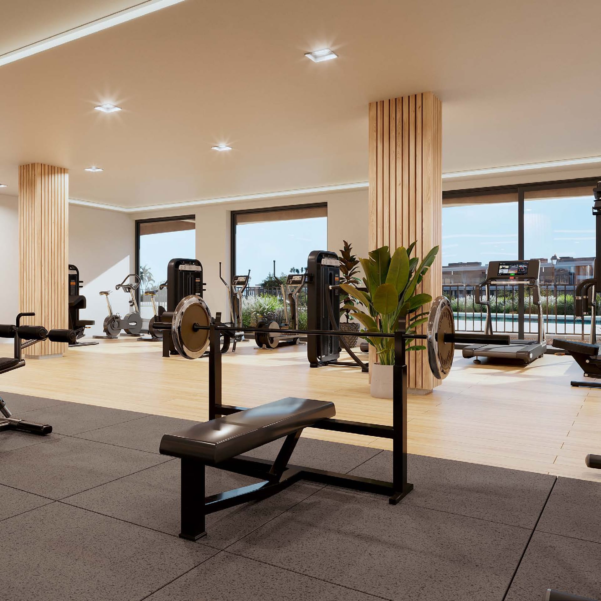 The gym, with weights and machines between timber-clad columns and windows looking onto the pool. Unika I, Buenas Noches, Estepona.