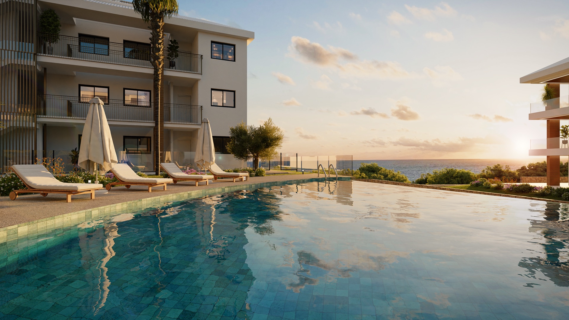 A pool at sunset, with loungers and parasols on one side and the sea in the distance. Unique Infinity, El Higuerón, Fuengirola.
