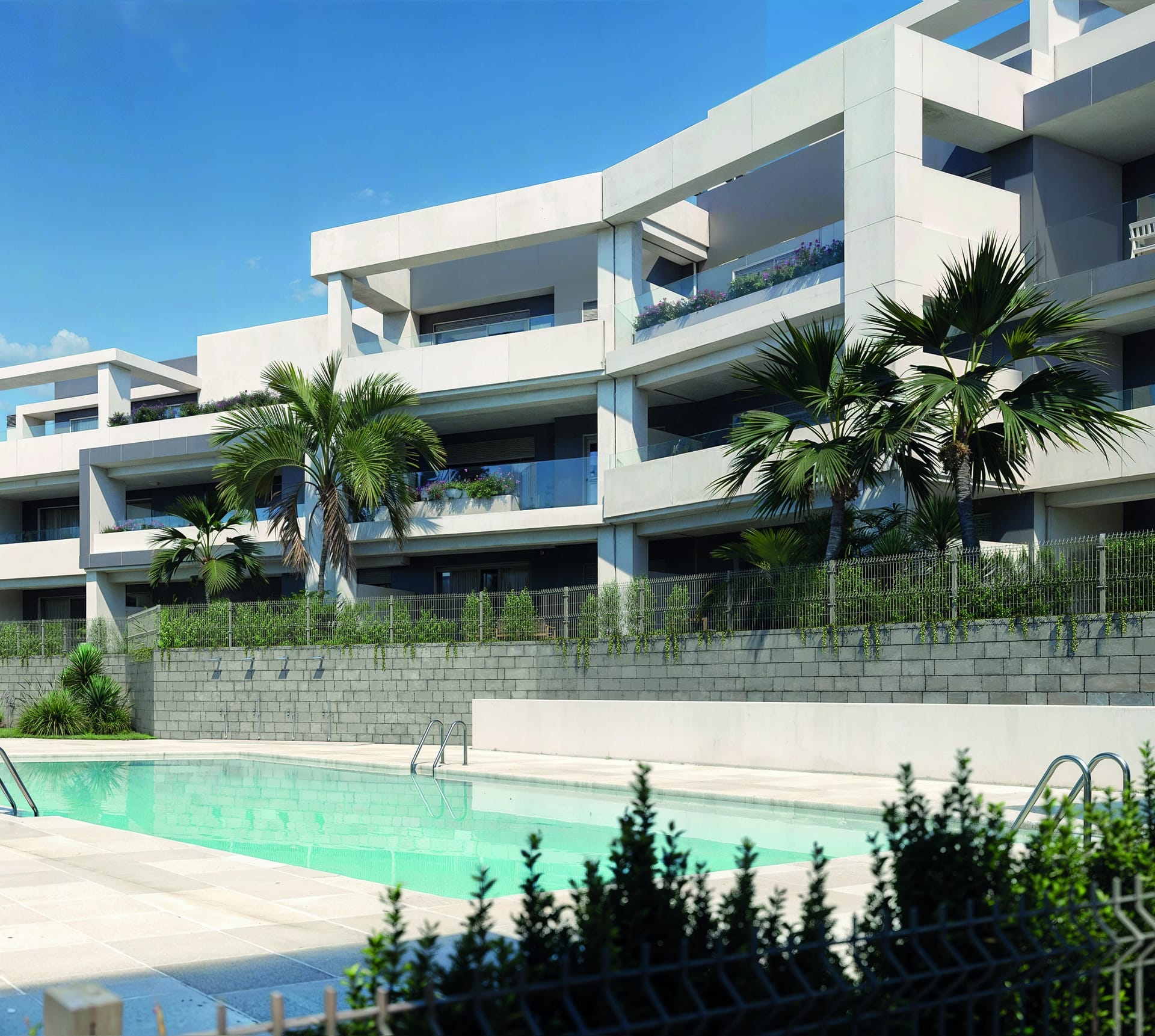 An outdoor pool laid out below the buildings, with palms in the gardens between. Vanian Gardens V, La Resina, Estepona.