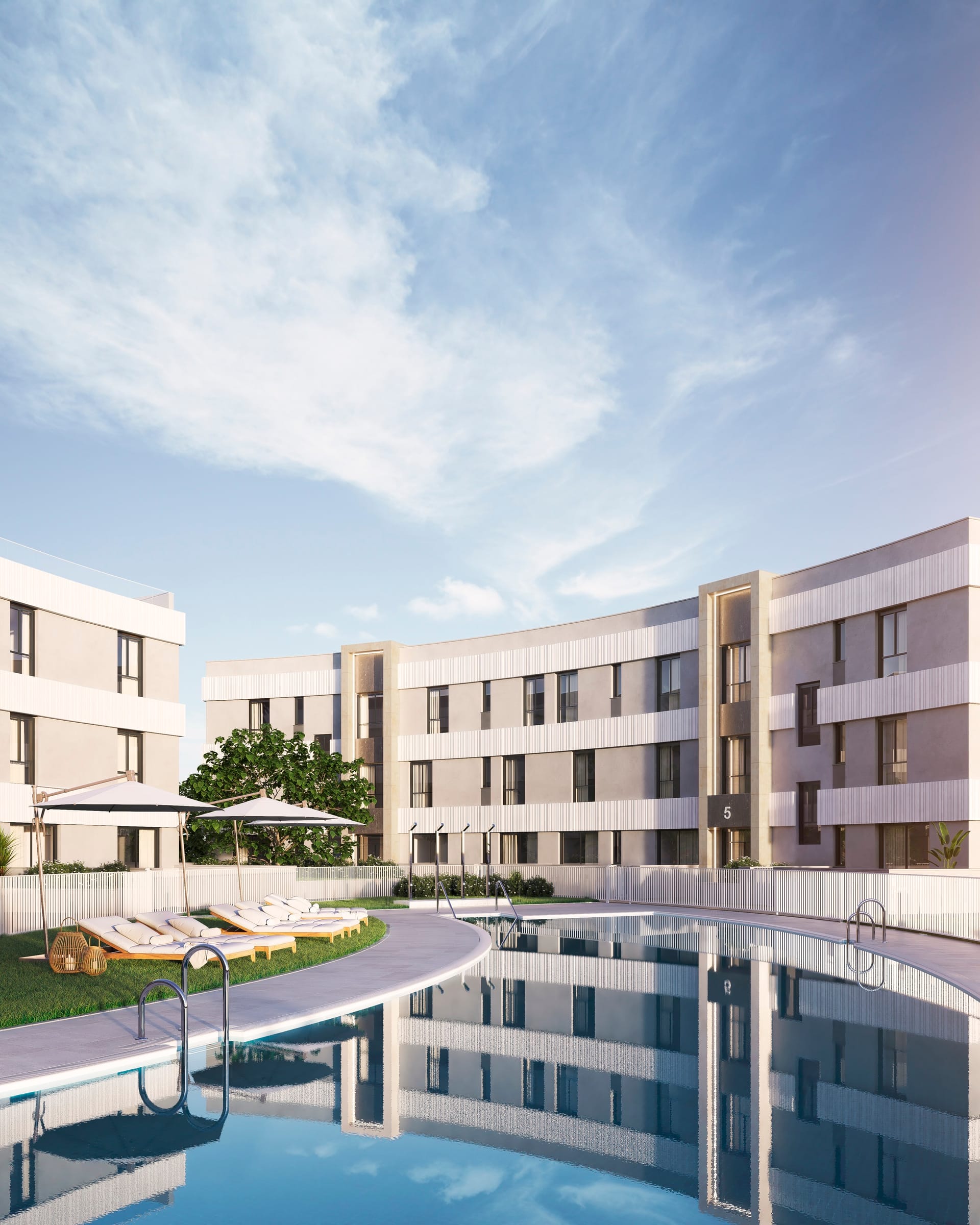 The pool and its gardens between two of the buildings, with sun umbrellas on the lawn. Vanian Views, La Resina, Estepona.